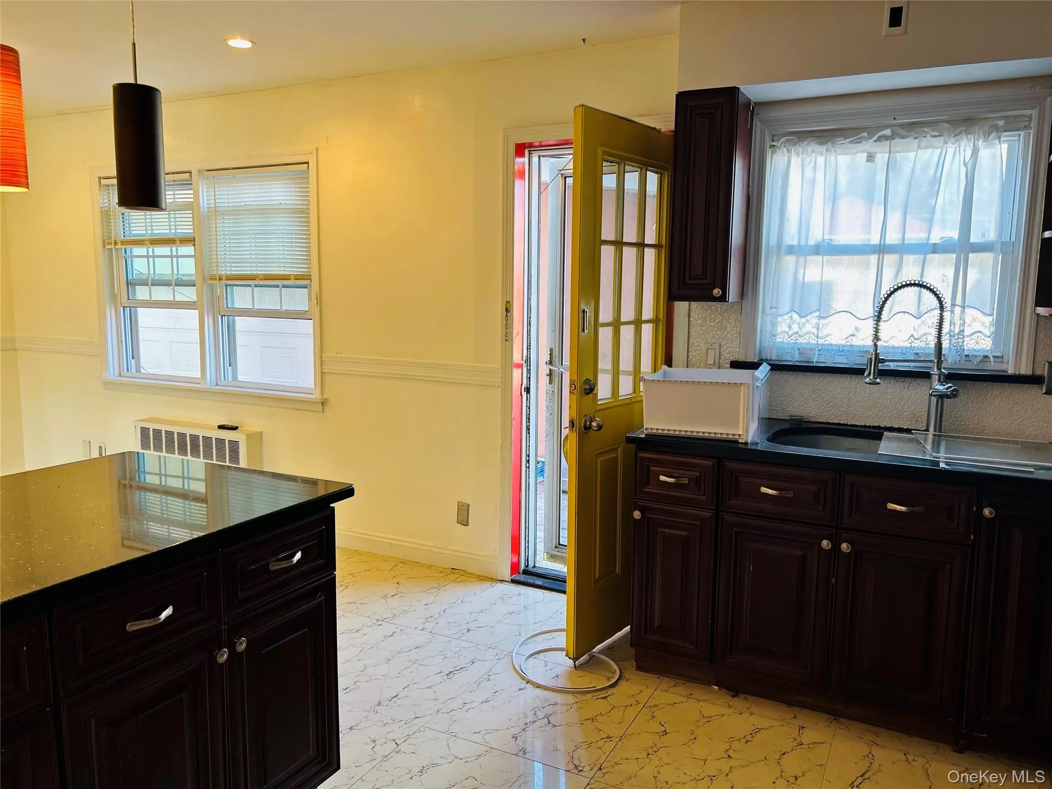 Kitchen featuring dark brown cabinetry, light marble finish flooring, dark stone counters, pendant lighting, and recessed lighting Kitchen featuring dark brown cabinetry, light marble finish flooring, dark stone counters, pendant lighting, and recessed lighting