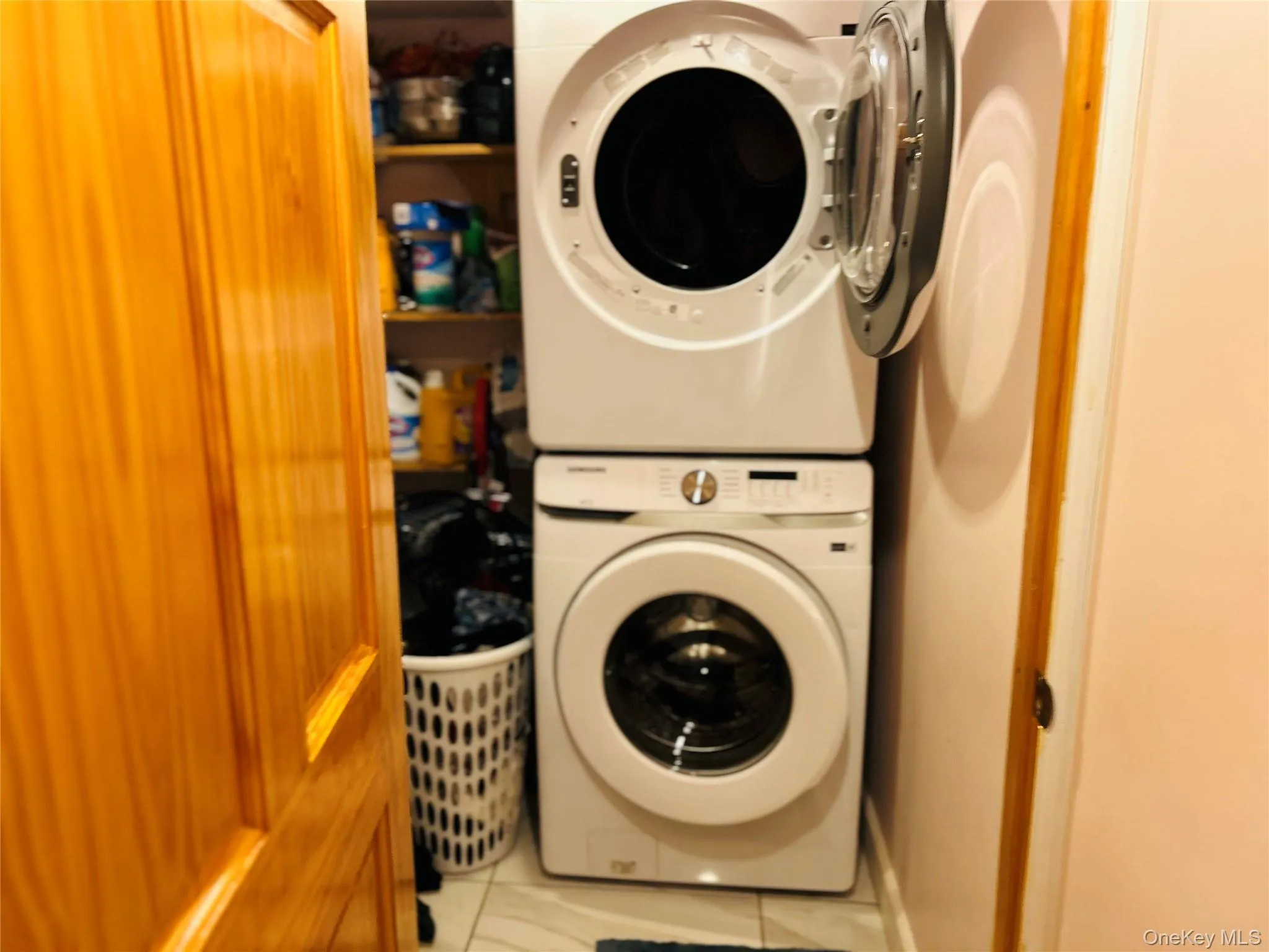 Laundry area featuring light tile patterned floors and stacked washer / dryer Laundry area featuring light tile patterned floors and stacked washer / dryer