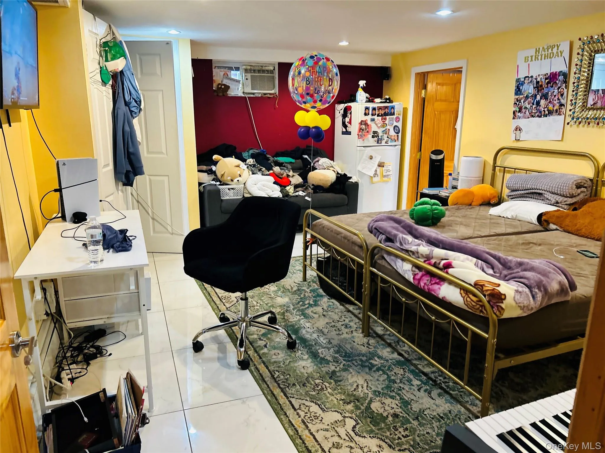 Bedroom featuring freestanding refrigerator, light tile patterned floors, and an office area Bedroom featuring freestanding refrigerator, light tile patterned floors, and an office area