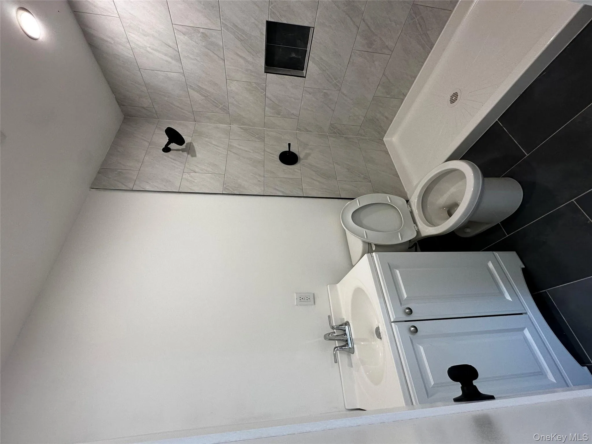 Full bath with vanity, a shower stall, and dark tile patterned flooring Full bath with vanity, a shower stall, and dark tile patterned flooring