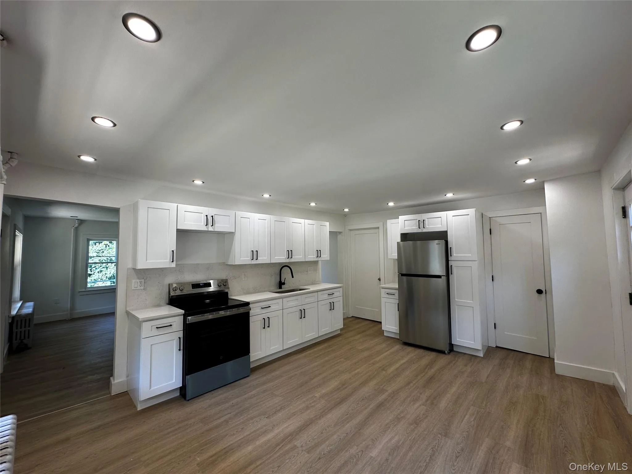 Kitchen featuring stainless steel appliances, white cabinetry, dark wood-type flooring, recessed lighting, and decorative backsplash Kitchen featuring stainless steel appliances, white cabinetry, dark wood-type flooring, recessed lighting, and decorative backsplash