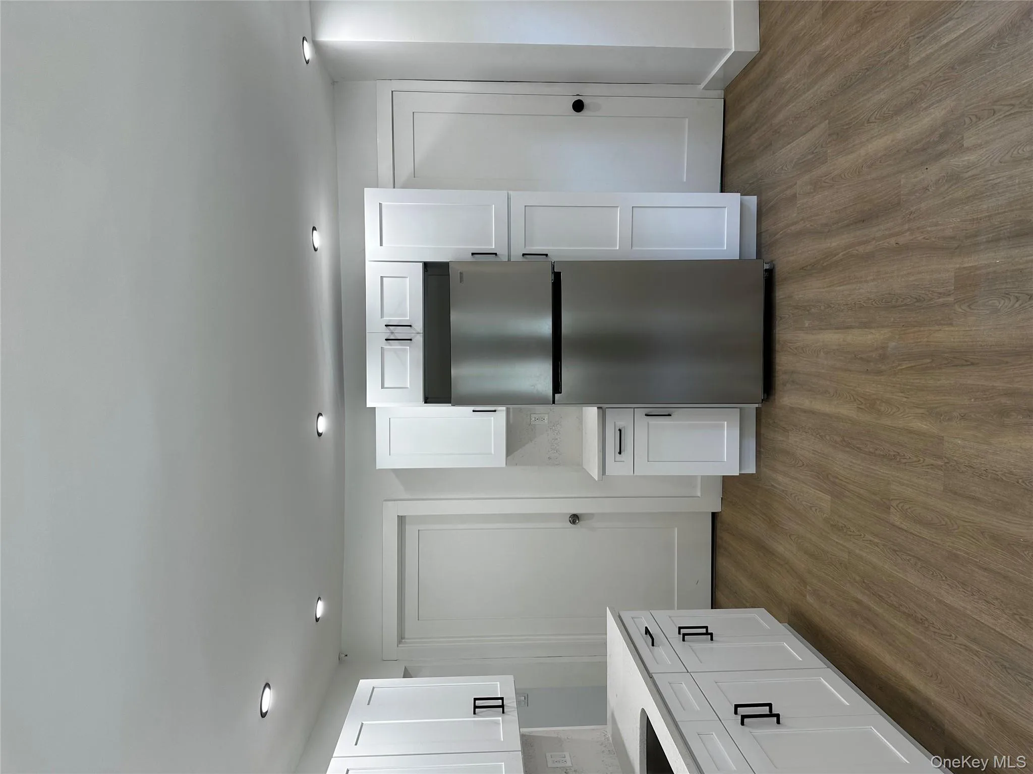 Kitchen with freestanding refrigerator, dark wood-type flooring, white cabinetry, recessed lighting, and backsplash Kitchen with freestanding refrigerator, dark wood-type flooring, white cabinetry, recessed lighting, and backsplash