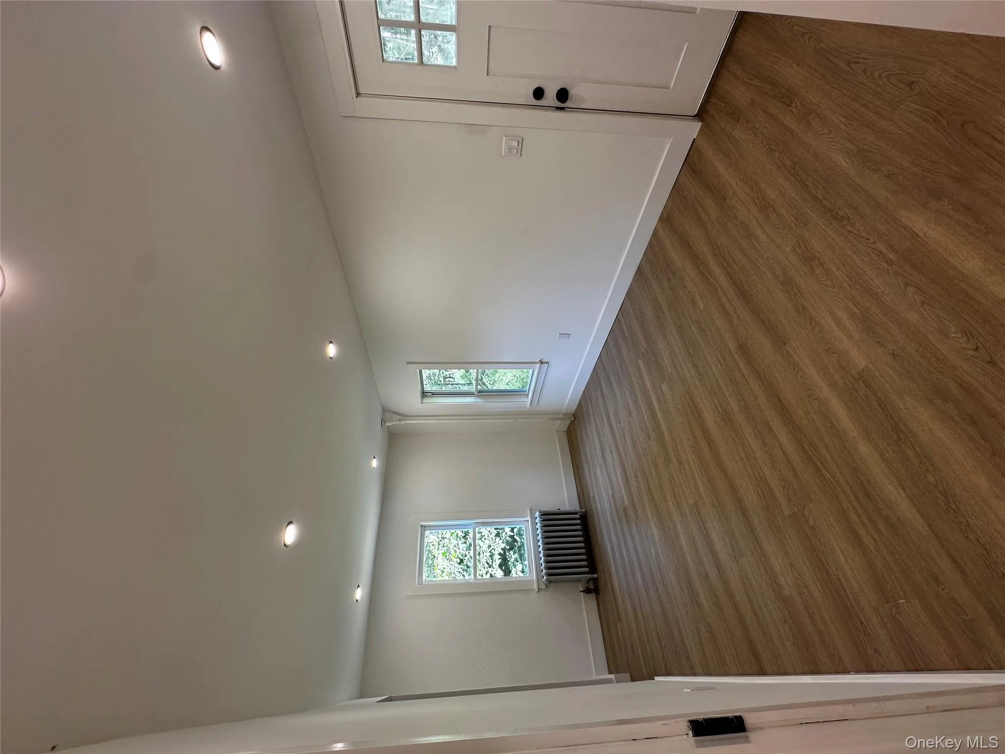 Unfurnished room featuring wood finished floors, radiator heating unit, and recessed lighting Unfurnished room featuring wood finished floors, radiator heating unit, and recessed lighting