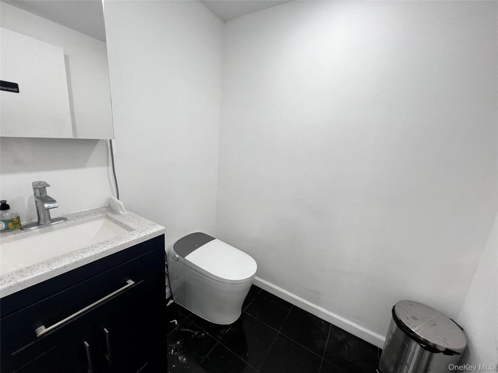 Half bath with vanity and dark tile patterned flooring Half bath with vanity and dark tile patterned flooring