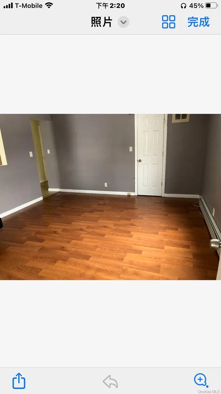 Unfurnished room with wood finished floors and baseboard heating Unfurnished room with wood finished floors and baseboard heating