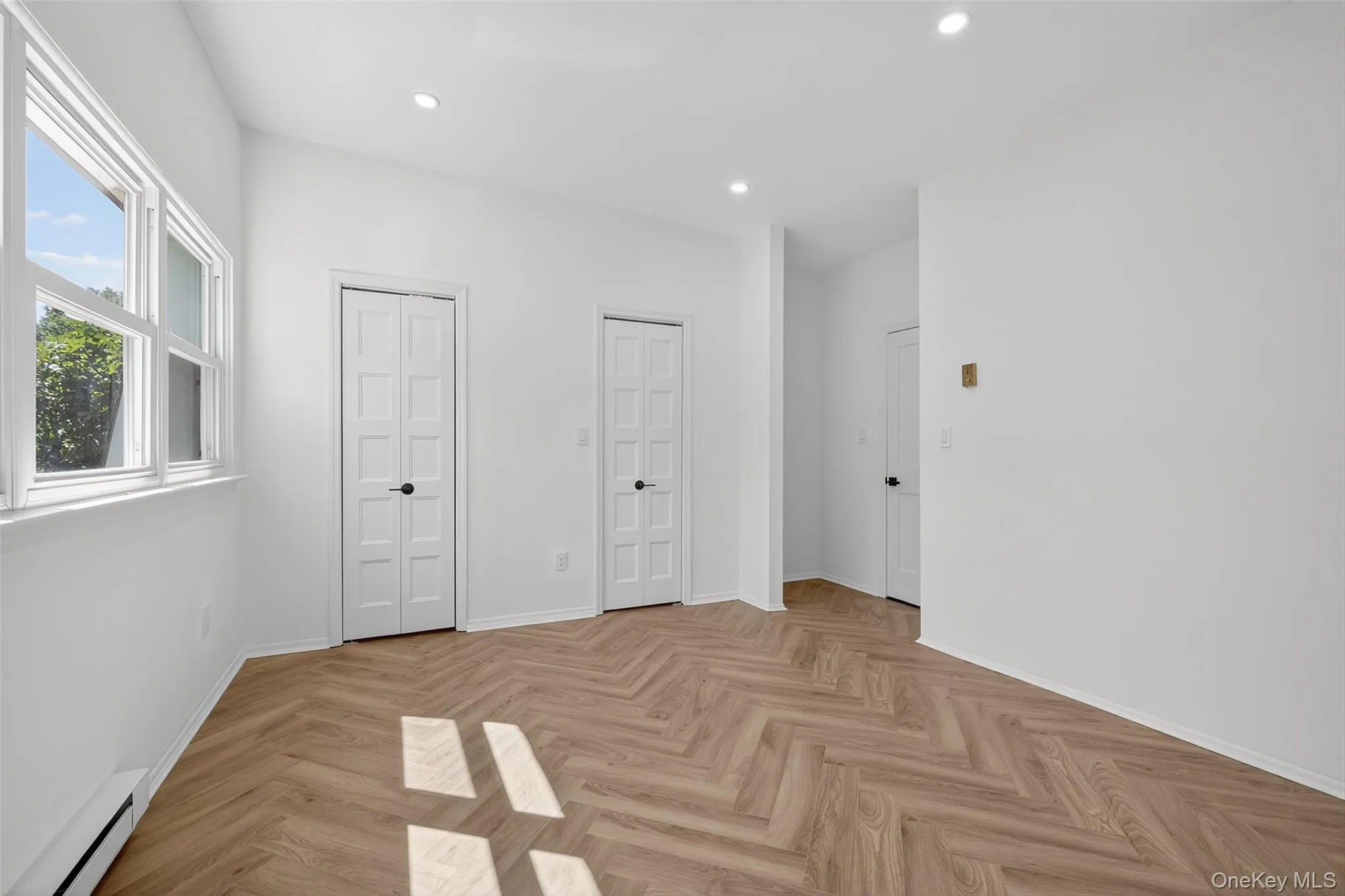 Unfurnished bedroom featuring two closets, a baseboard radiator, and recessed lighting Unfurnished bedroom featuring two closets, a baseboard radiator, and recessed lighting