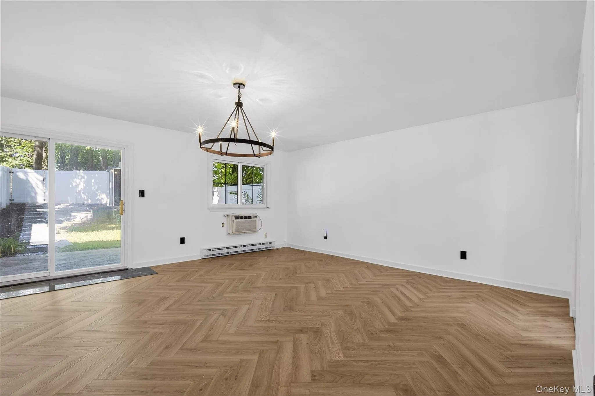 Unfurnished room featuring a chandelier, a baseboard heating unit, and an AC wall unit Unfurnished room featuring a chandelier, a baseboard heating unit, and an AC wall unit