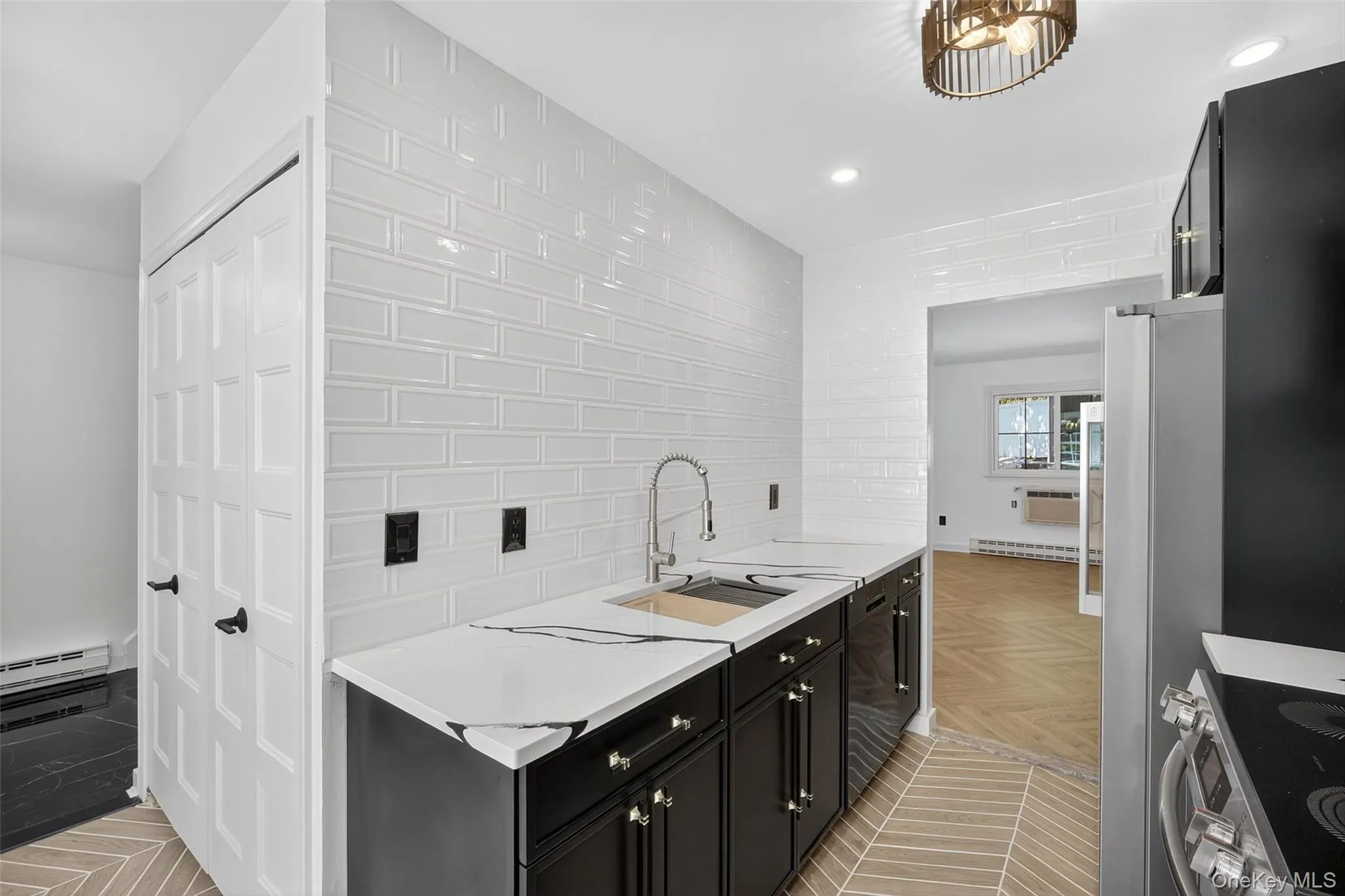 Kitchen with dark cabinetry, stainless steel appliances, baseboard heating, recessed lighting, and light stone countertops Kitchen with dark cabinetry, stainless steel appliances, baseboard heating, recessed lighting, and light stone countertops