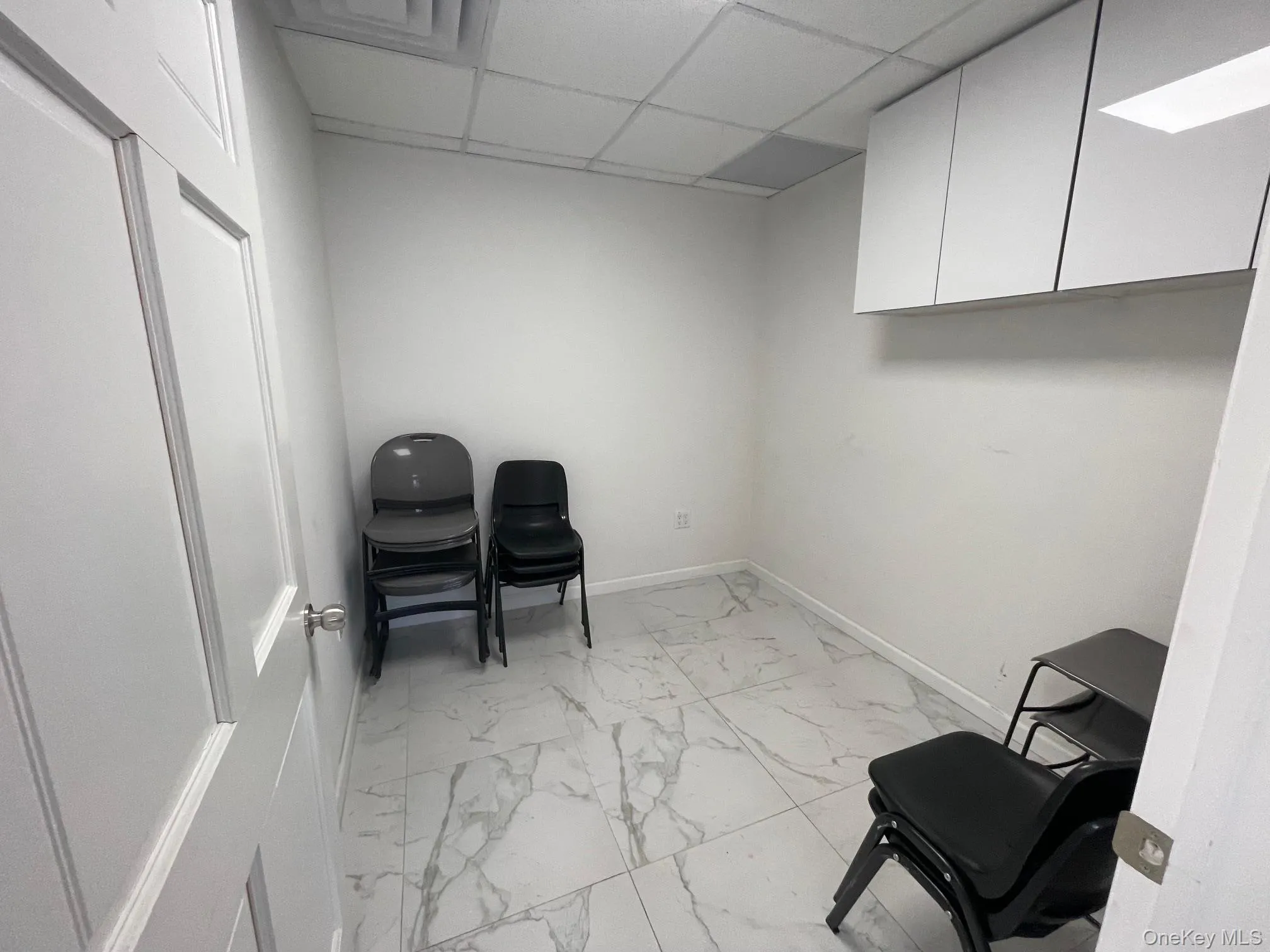 Sitting room with a drop ceiling and light marble finish floors Sitting room with a drop ceiling and light marble finish floors