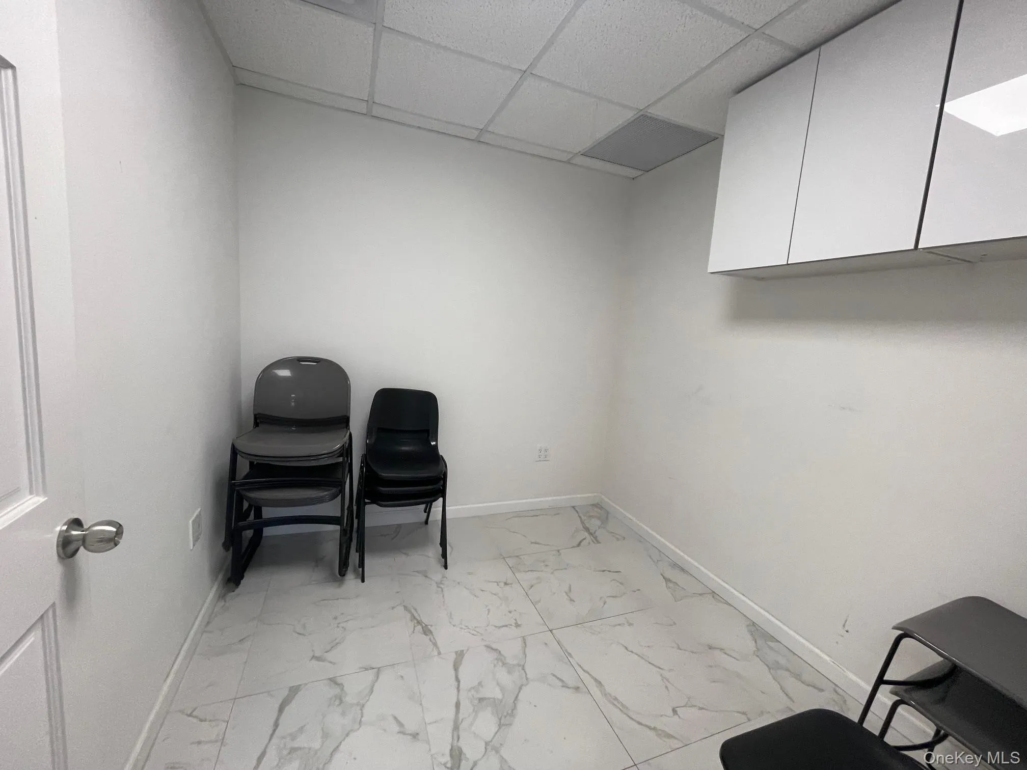 Home office featuring a drop ceiling and light marble finish floors Home office featuring a drop ceiling and light marble finish floors