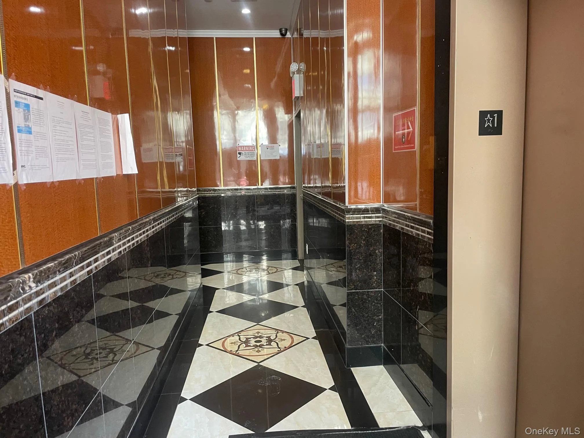 Hallway with elevator, inlaid floor details, and tile patterned floors Hallway with elevator, inlaid floor details, and tile patterned floors