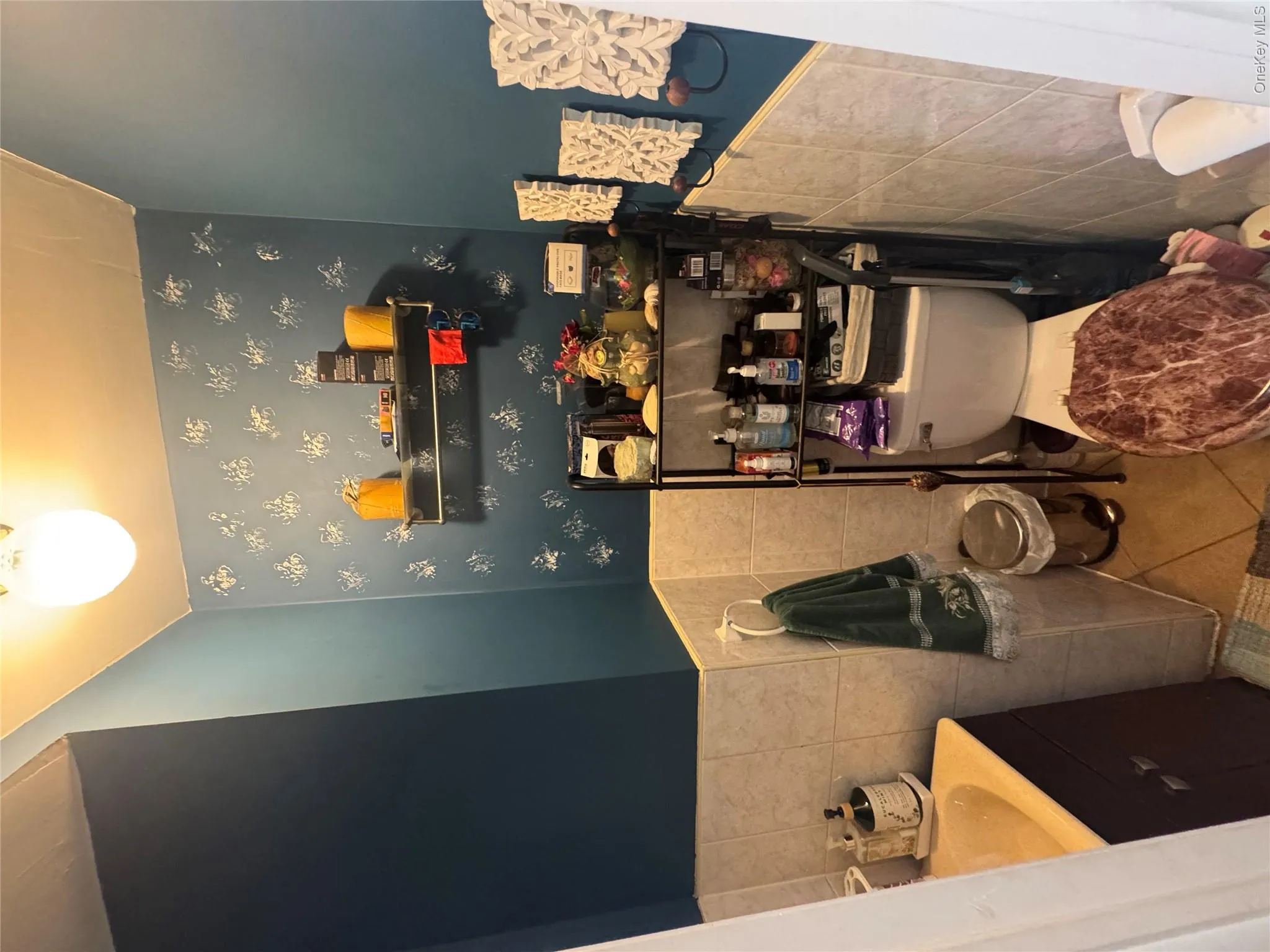 Half bath featuring light tile patterned floors, tile walls, vanity, and a wainscoted wall Half bath featuring light tile patterned floors, tile walls, vanity, and a wainscoted wall