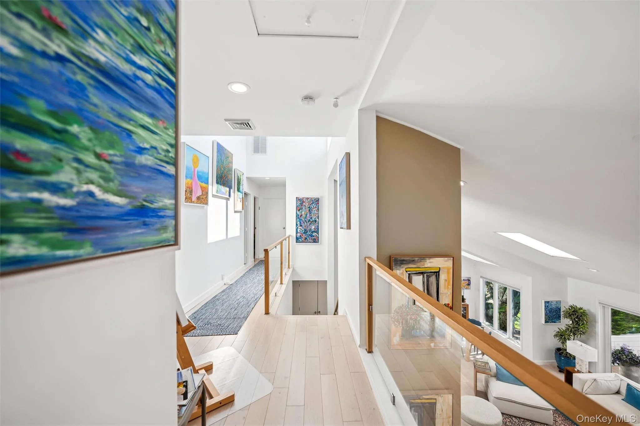 Hall with an upstairs landing, recessed lighting, light wood-type flooring, and a skylight Hall with an upstairs landing, recessed lighting, light wood-type flooring, and a skylight