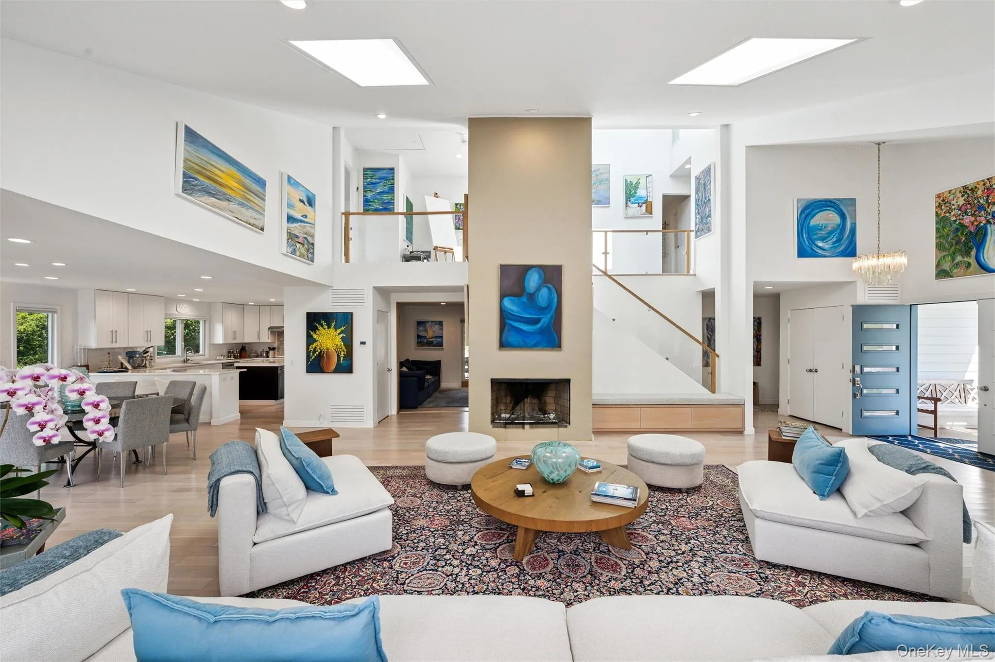 Living room featuring a high ceiling, recessed lighting, light wood finished floors, a chandelier, and a fireplace Living room featuring a high ceiling, recessed lighting, light wood finished floors, a chandelier, and a fireplace