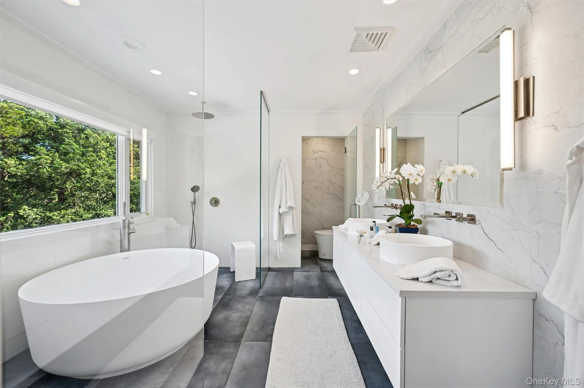 Bathroom featuring double vanity, a freestanding bath, tile walls, a marble finish shower, and recessed lighting Bathroom featuring double vanity, a freestanding bath, tile walls, a marble finish shower, and recessed lighting