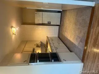 Kitchen featuring fridge, white cabinetry, oven, tile walls, and light countertops Kitchen featuring fridge, white cabinetry, oven, tile walls, and light countertops