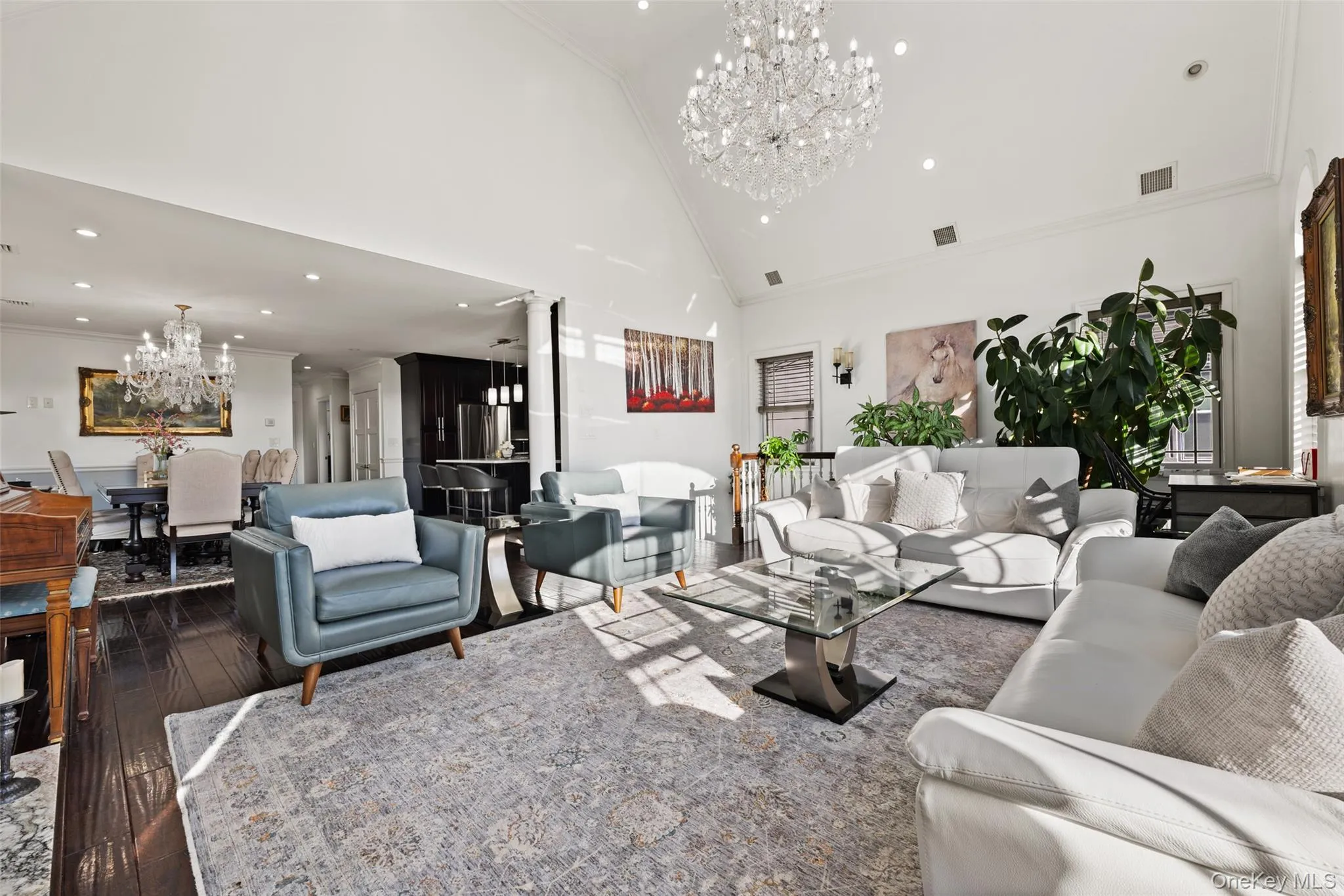 Living room featuring a chandelier, crown molding, high vaulted ceiling, dark wood-style flooring, and recessed lighting Living room featuring a chandelier, crown molding, high vaulted ceiling, dark wood-style flooring, and recessed lighting