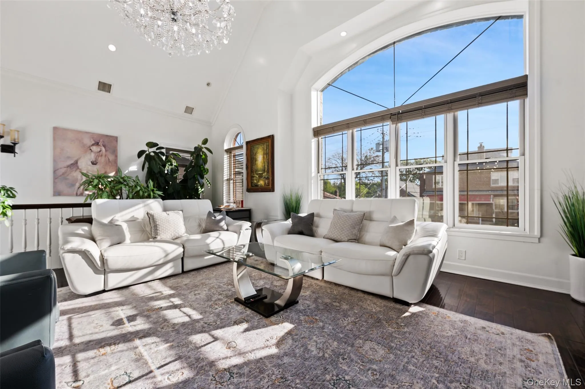 Living area featuring high vaulted ceiling, wood finished floors, recessed lighting, and a chandelier Living area featuring high vaulted ceiling, wood finished floors, recessed lighting, and a chandelier