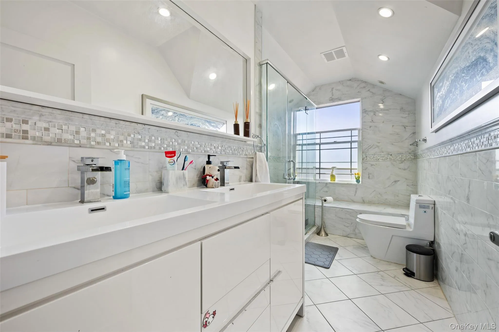 Bathroom with tile walls, a stall shower, double vanity, lofted ceiling, and recessed lighting Bathroom with tile walls, a stall shower, double vanity, lofted ceiling, and recessed lighting