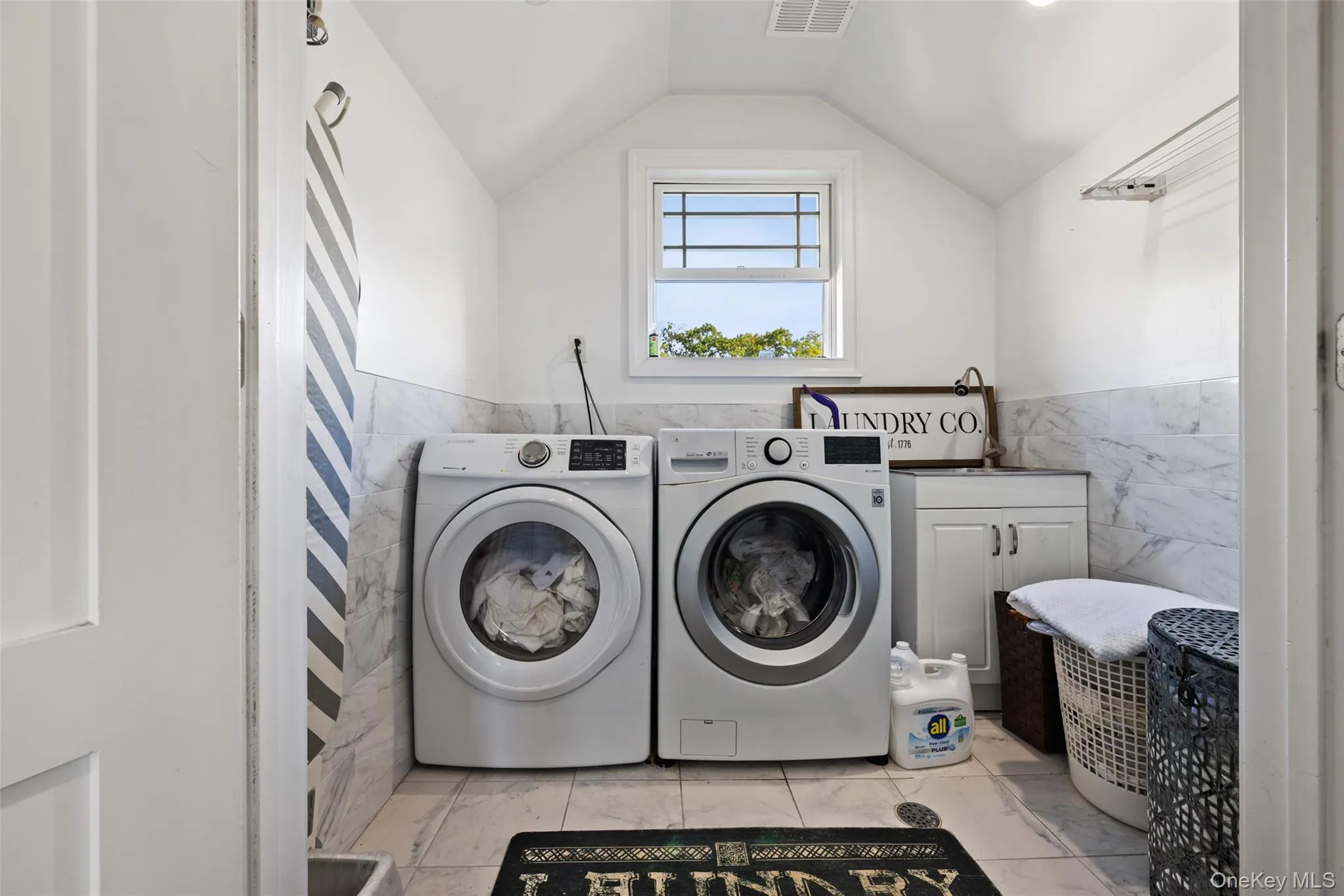 Laundry area with tile walls, a wainscoted wall, and independent washer and dryer Laundry area with tile walls, a wainscoted wall, and independent washer and dryer