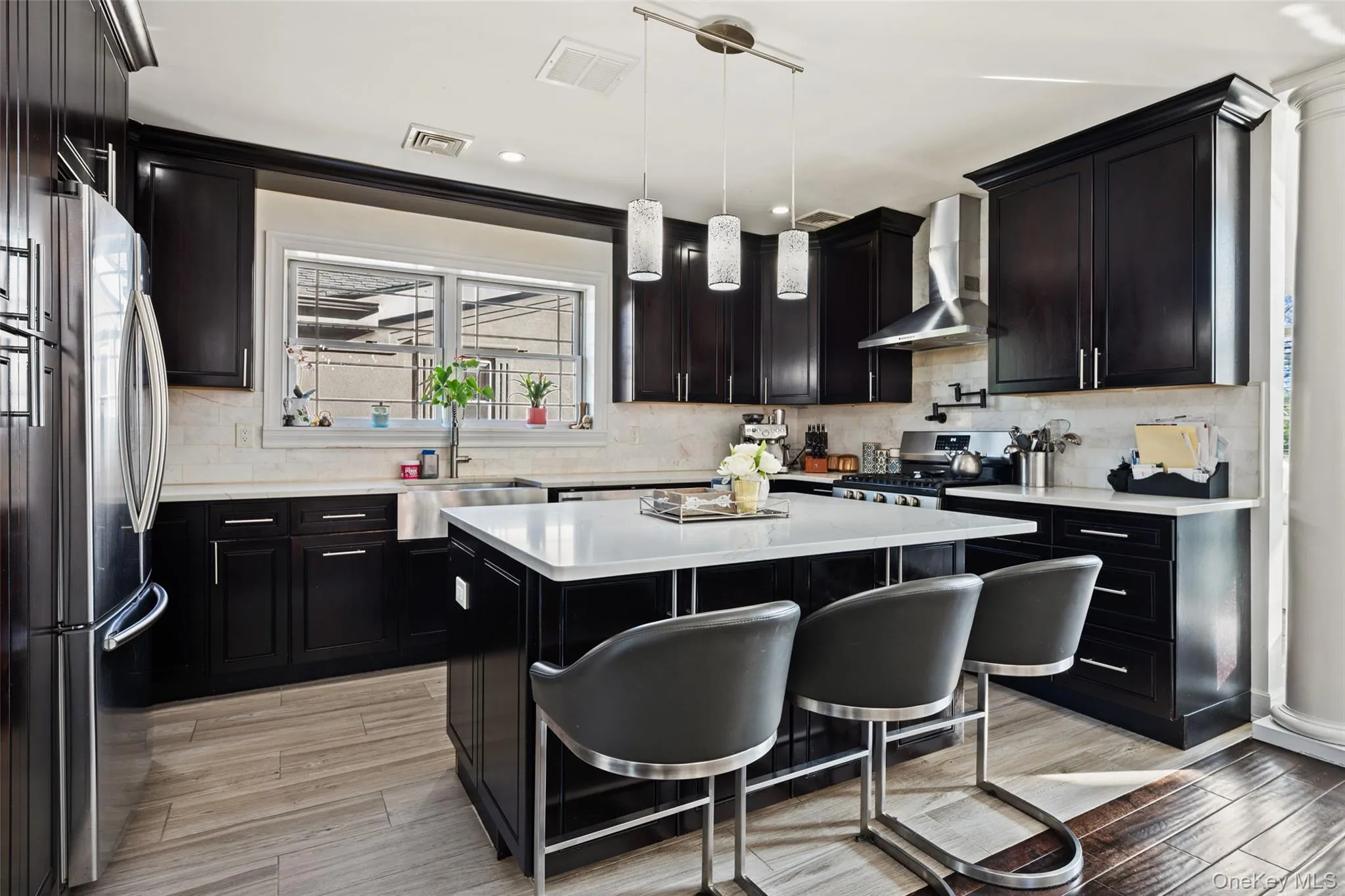 Kitchen featuring dark cabinets, a breakfast bar area, backsplash, pendant lighting, and recessed lighting Kitchen featuring dark cabinets, a breakfast bar area, backsplash, pendant lighting, and recessed lighting