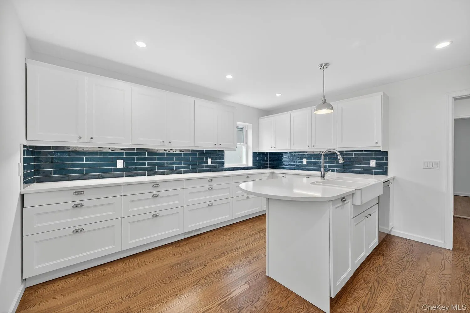 Kitchen featuring white cabinets, hanging light fixtures, tasteful backsplash, light wood-style flooring, and recessed lighting Kitchen featuring white cabinets, hanging light fixtures, tasteful backsplash, light wood-style flooring, and recessed lighting