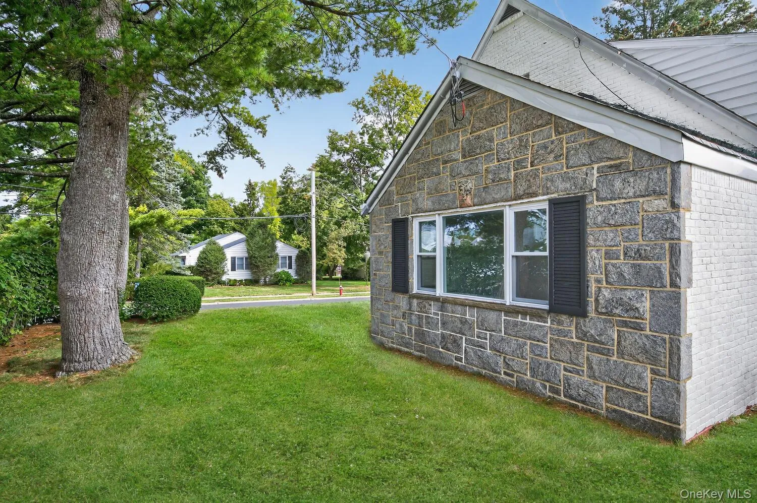 View of home's exterior featuring stone siding and a lawn View of home's exterior featuring stone siding and a lawn