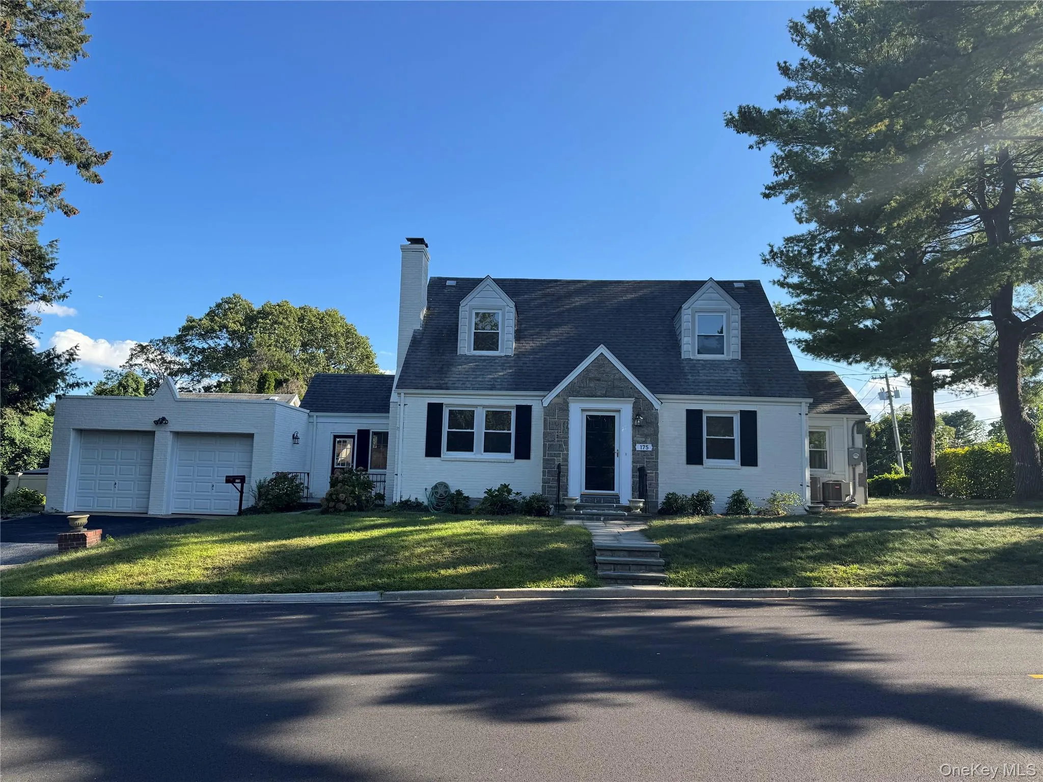 Cape cod house with a front lawn, a chimney, asphalt driveway, and an attached garage Cape cod house with a front lawn, a chimney, asphalt driveway, and an attached garage