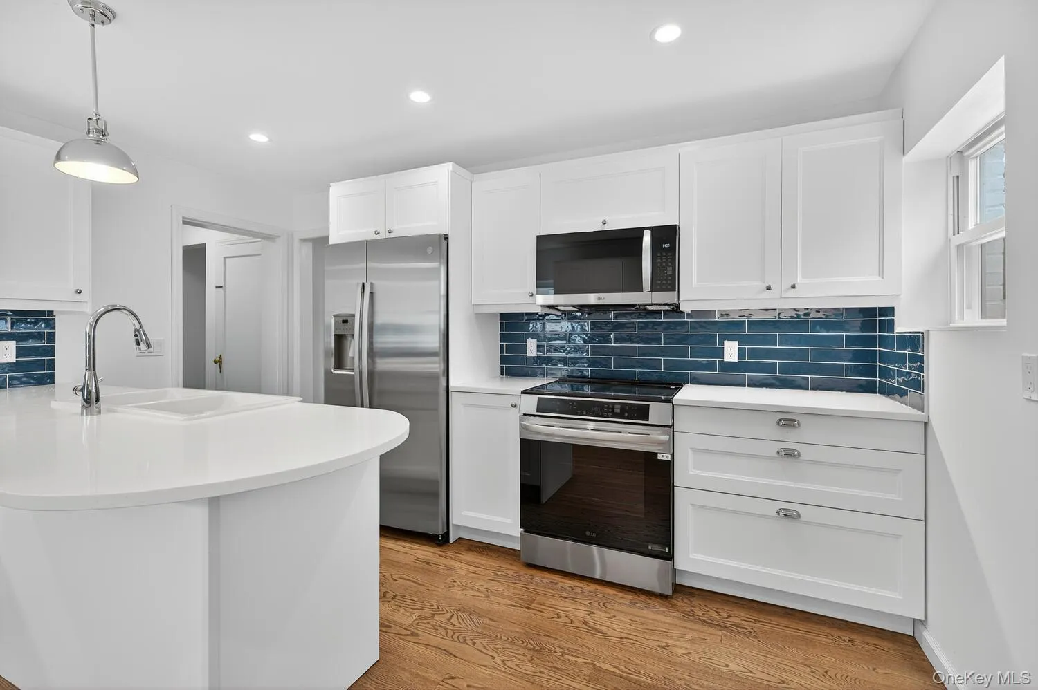 Newly renovated Kitchen with white cabinets, appliances with stainless steel finishes, tasteful backsplash, hanging light fixtures, and recessed lighting Newly renovated Kitchen with white cabinets, appliances with stainless steel finishes, tasteful backsplash, hanging light fixtures, and recessed lighting