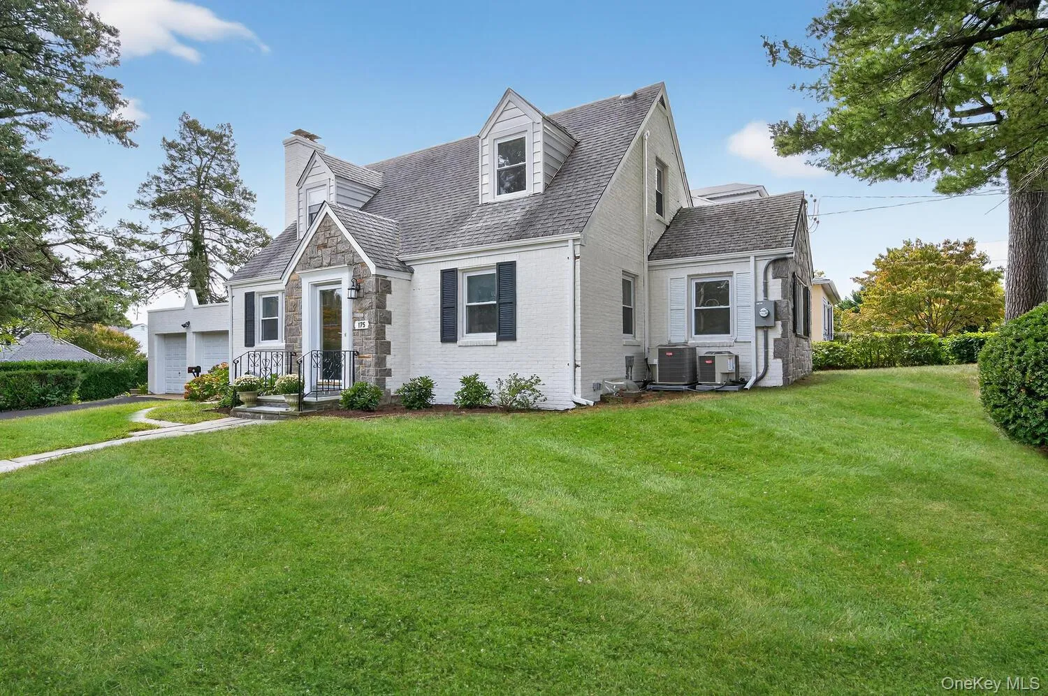 Cape cod home with a chimney, a front lawn, a garage, brick siding, and a shingled roof Cape cod home with a chimney, a front lawn, a garage, brick siding, and a shingled roof