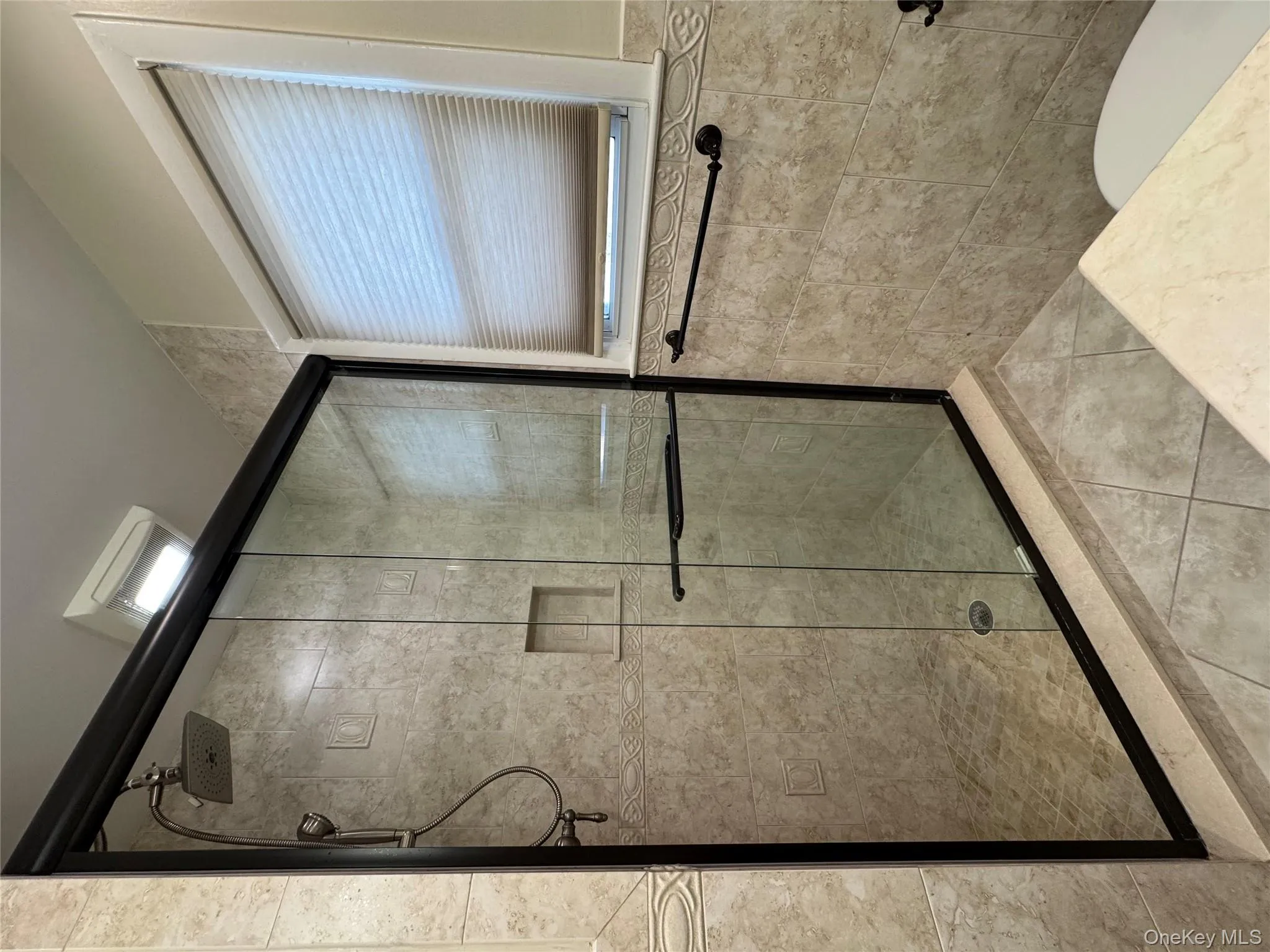 Bathroom with a shower stall, tile patterned floors, and tile walls Bathroom with a shower stall, tile patterned floors, and tile walls