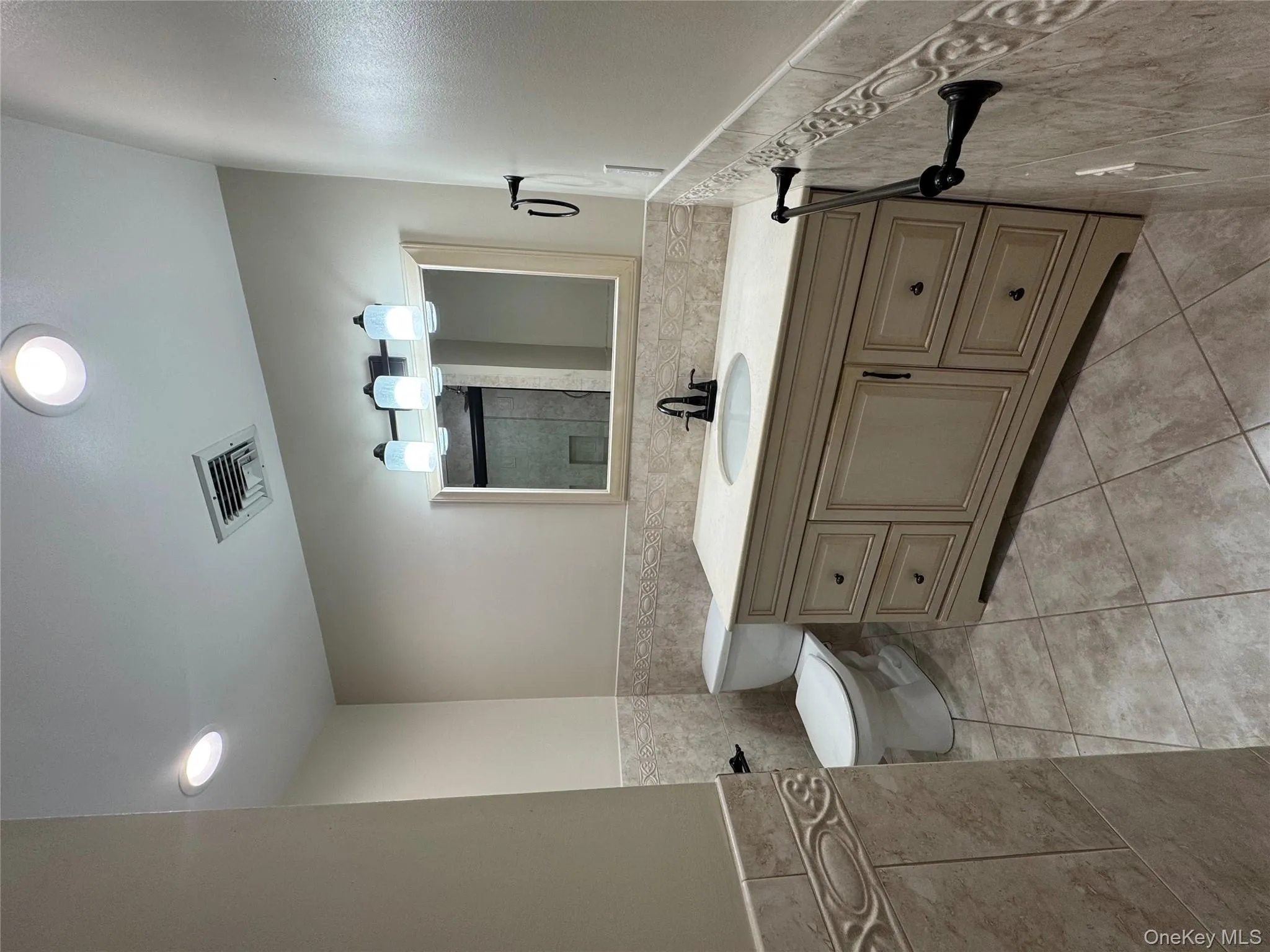 Bathroom featuring tile walls, a wainscoted wall, vanity, light tile patterned floors, and recessed lighting Bathroom featuring tile walls, a wainscoted wall, vanity, light tile patterned floors, and recessed lighting