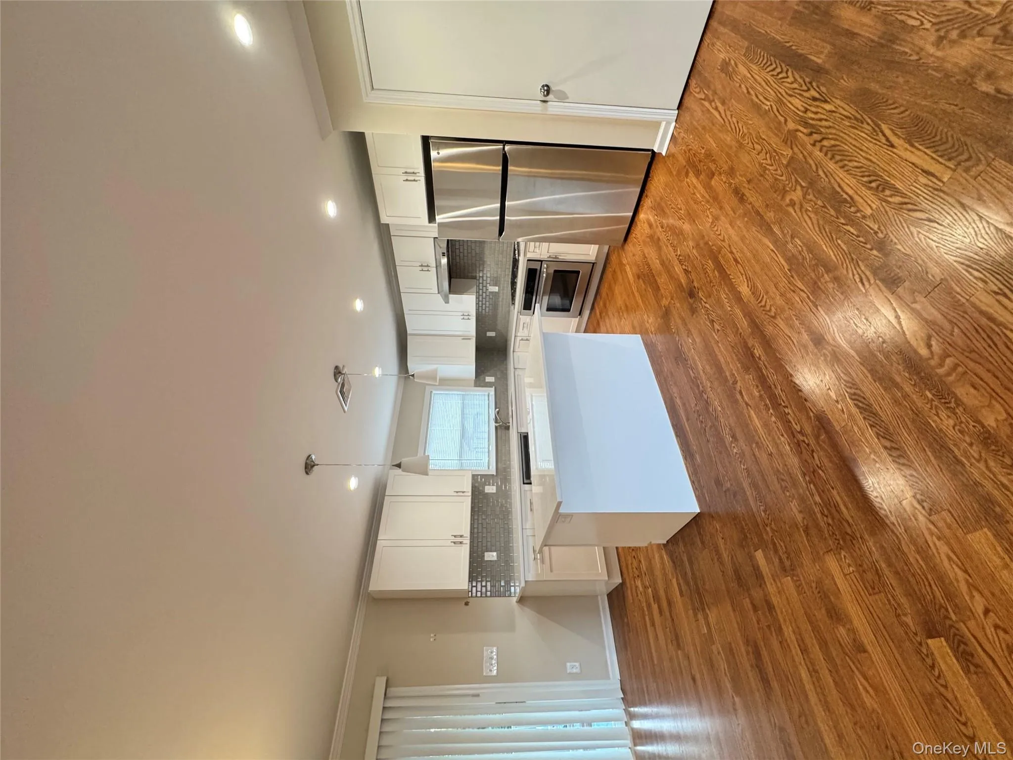 Kitchen featuring ornamental molding, white cabinetry, decorative light fixtures, fridge, and a center island Kitchen featuring ornamental molding, white cabinetry, decorative light fixtures, fridge, and a center island