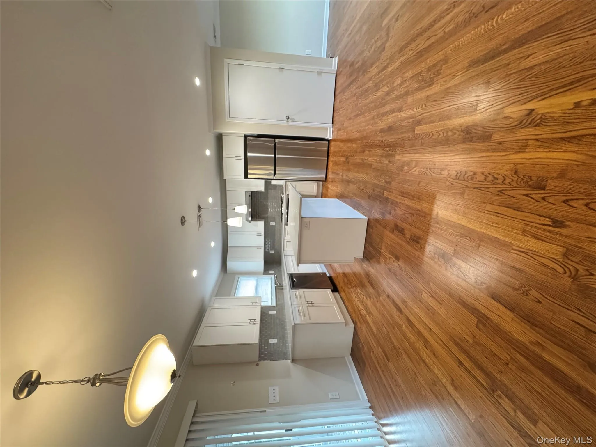 Kitchen featuring open floor plan, a center island, fridge, decorative light fixtures, and white cabinetry Kitchen featuring open floor plan, a center island, fridge, decorative light fixtures, and white cabinetry