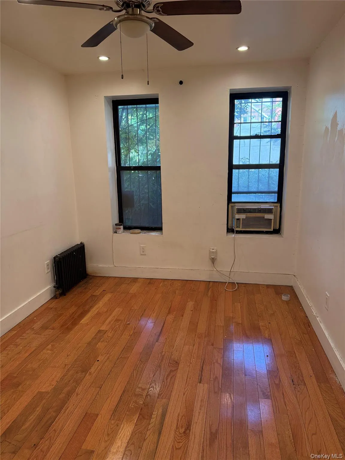 Spare room featuring hardwood / wood-style floors, plenty of natural light, radiator, recessed lighting, and a ceiling fan Spare room featuring hardwood / wood-style floors, plenty of natural light, radiator, recessed lighting, and a ceiling fan