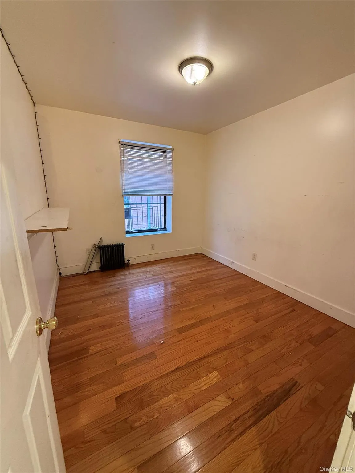 Unfurnished room featuring wood-type flooring and radiator Unfurnished room featuring wood-type flooring and radiator