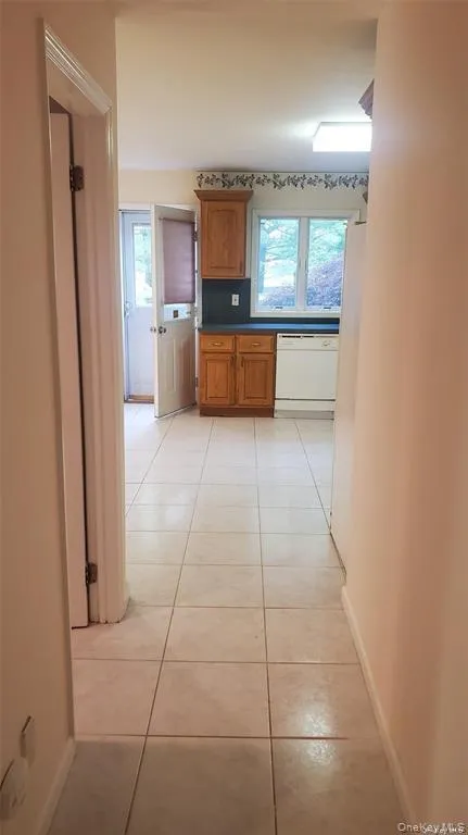 Hall featuring light tile patterned floors and plenty of natural light Hall featuring light tile patterned floors and plenty of natural light