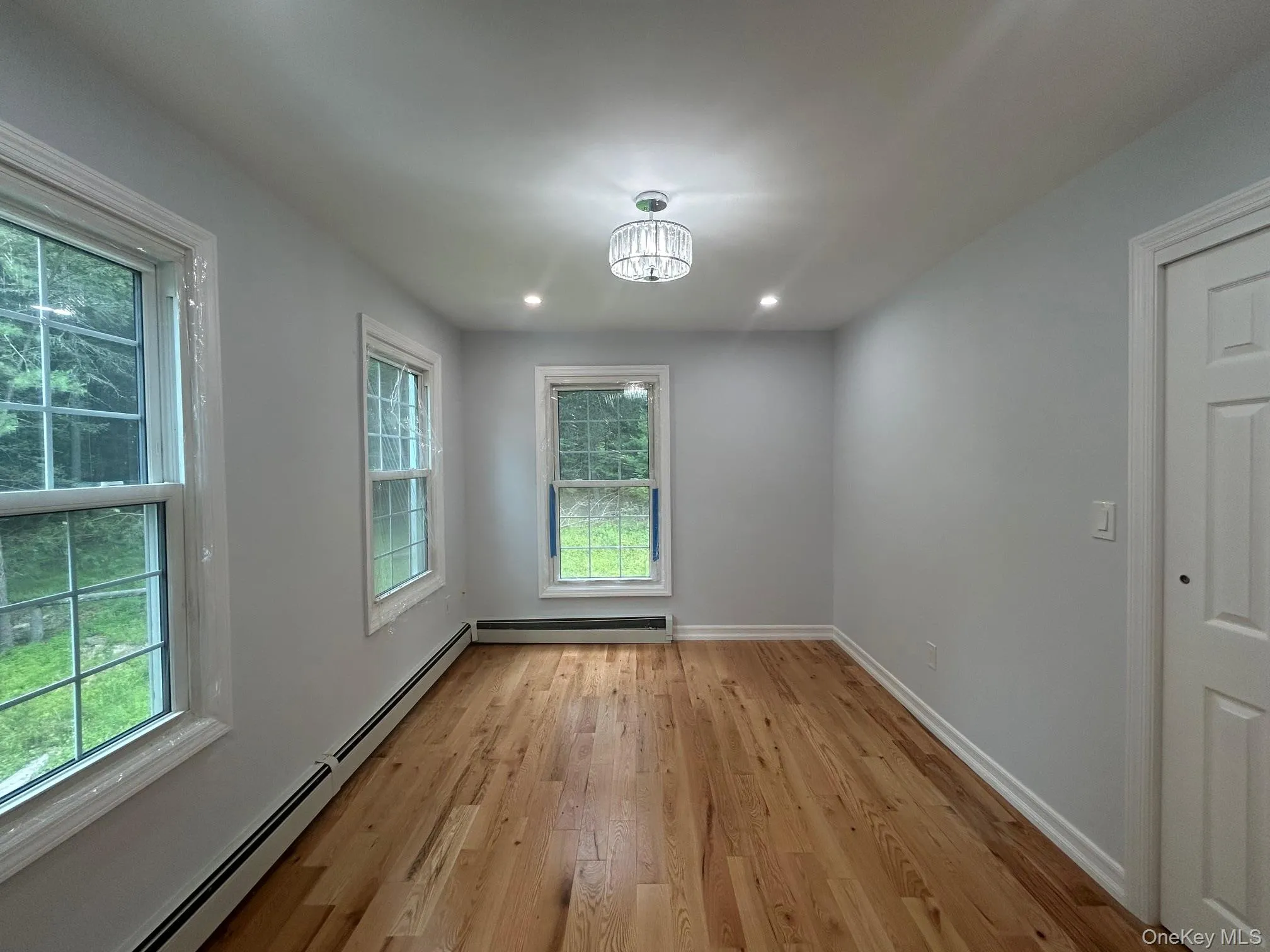 Unfurnished dining area featuring a baseboard radiator, light wood finished floors, a chandelier, and recessed lighting Unfurnished dining area featuring a baseboard radiator, light wood finished floors, a chandelier, and recessed lighting
