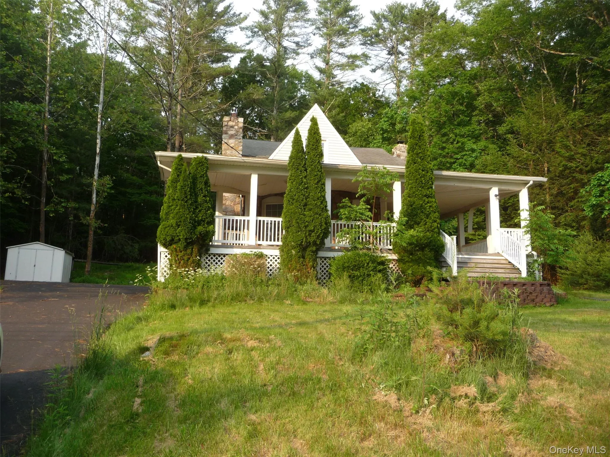 View of front facade with a chimney, a large porch, a storage unit, and a front lawn View of front facade with a chimney, a large porch, a storage unit, and a front lawn