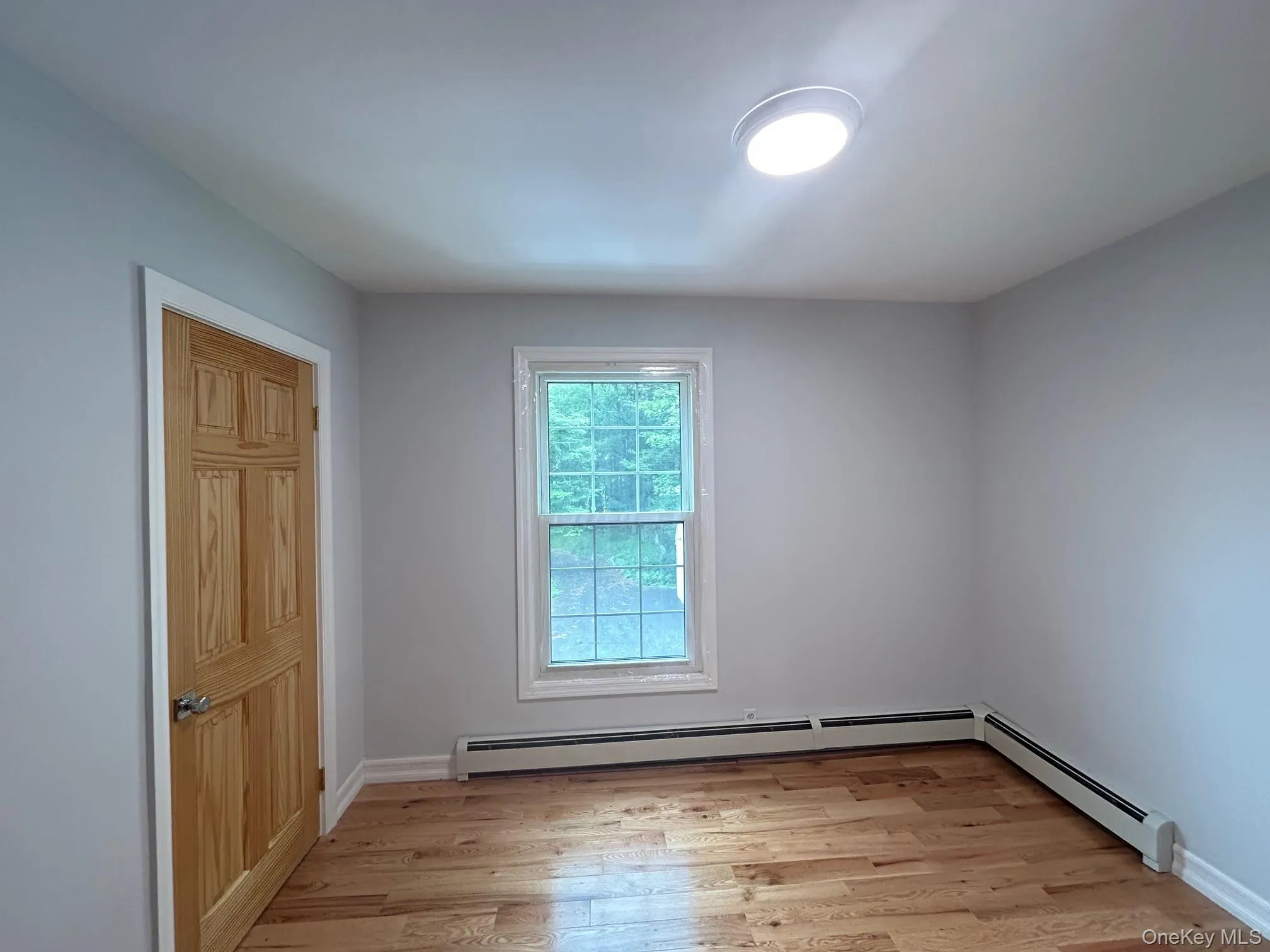 Spare room featuring light wood finished floors and a baseboard heating unit Spare room featuring light wood finished floors and a baseboard heating unit