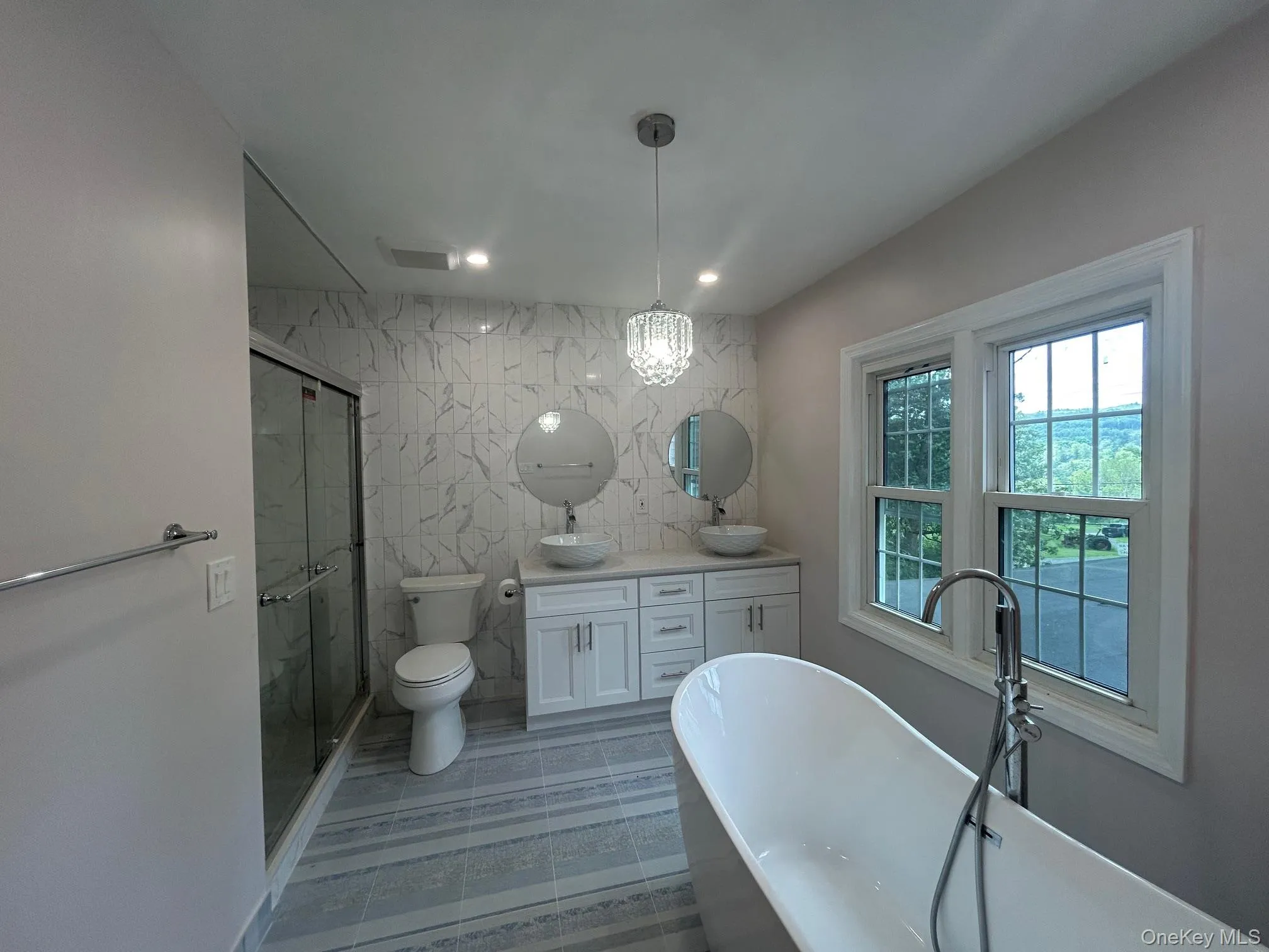 Bathroom with a soaking tub, tile walls, double vanity, a marble finish shower, and recessed lighting Bathroom with a soaking tub, tile walls, double vanity, a marble finish shower, and recessed lighting