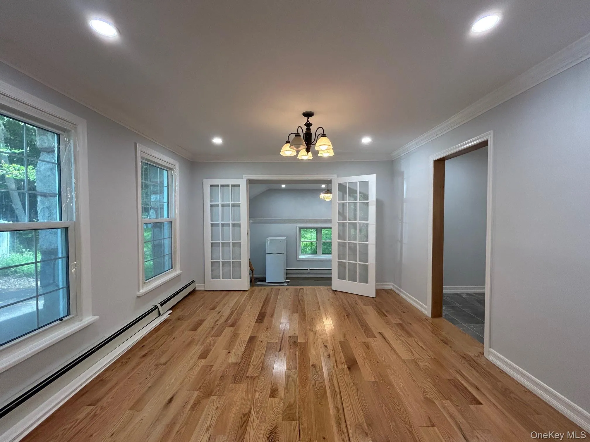 Unfurnished dining area with a baseboard radiator, a chandelier, light wood-style floors, ornamental molding, and recessed lighting Unfurnished dining area with a baseboard radiator, a chandelier, light wood-style floors, ornamental molding, and recessed lighting