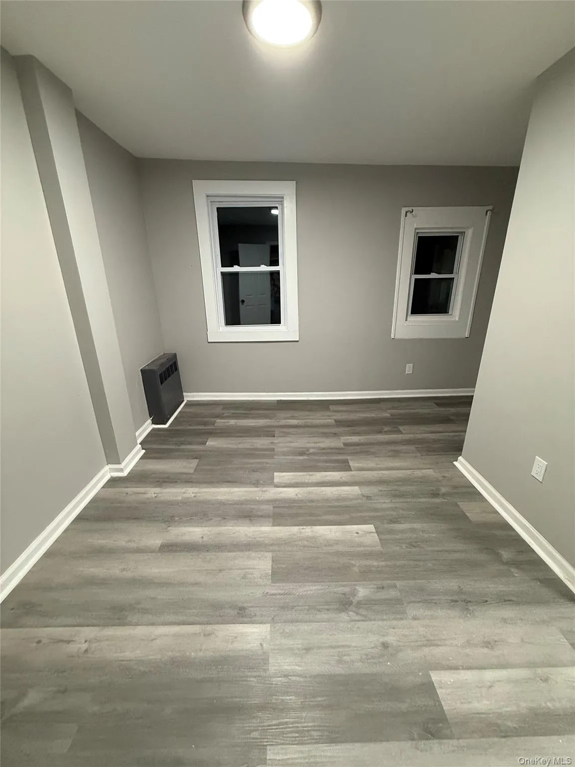 Empty room featuring light wood-style flooring and heating unit Empty room featuring light wood-style flooring and heating unit