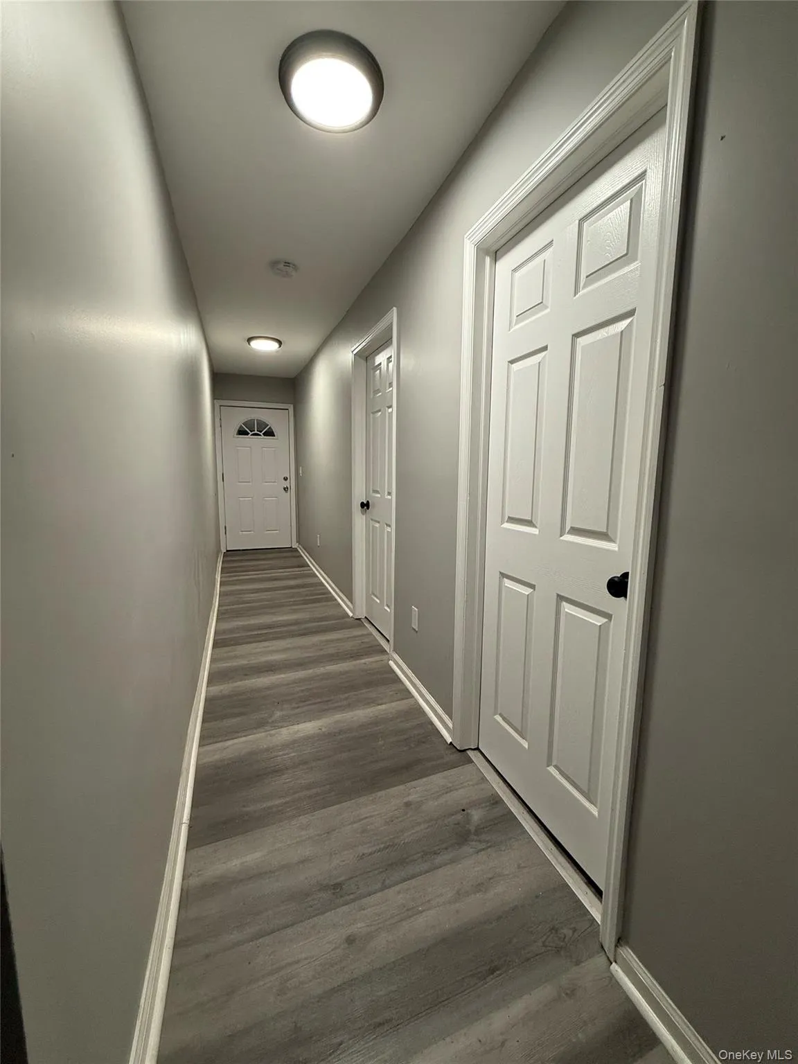 Hallway with baseboards and dark wood-type flooring Hallway with baseboards and dark wood-type flooring