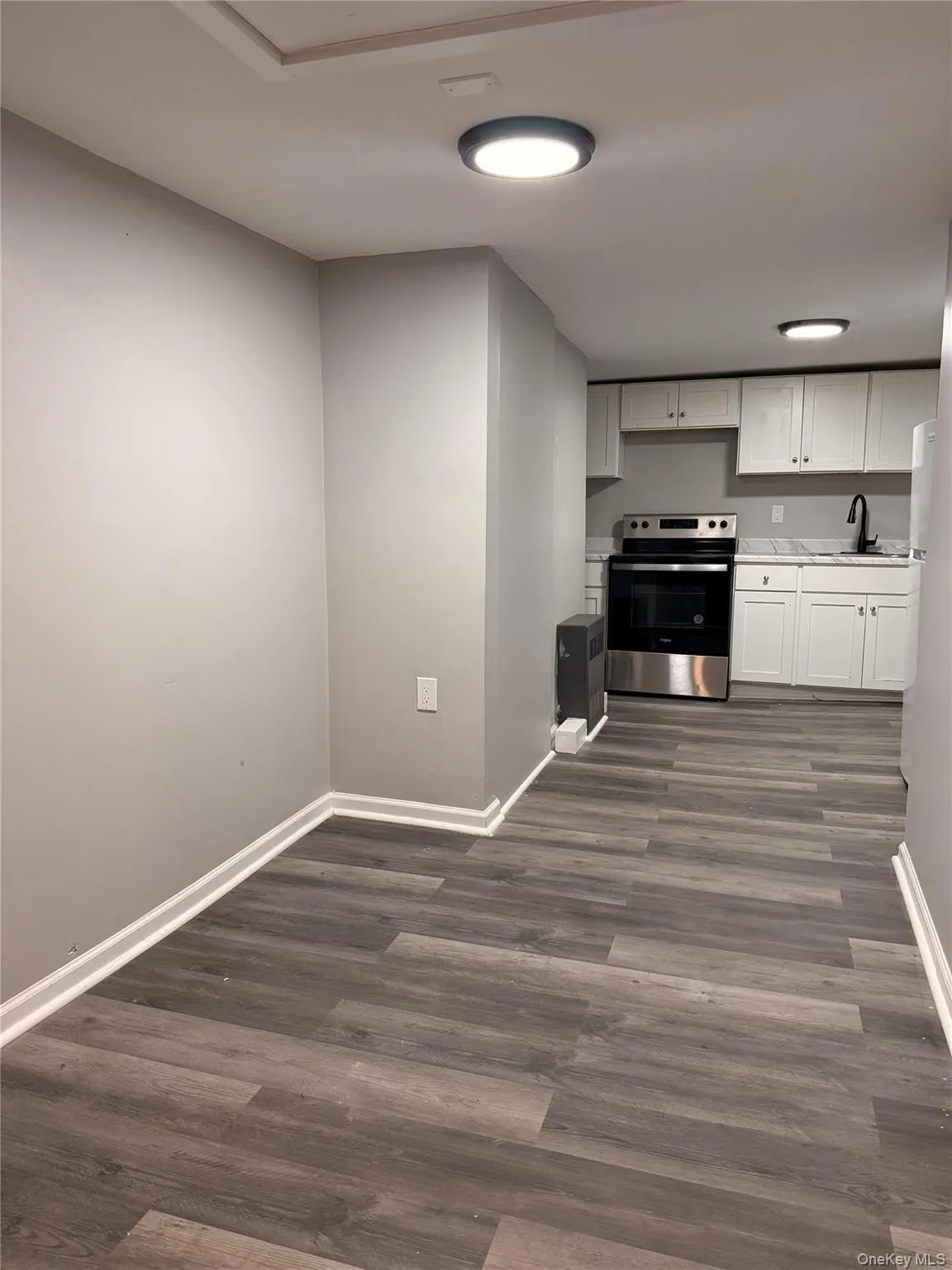 Kitchen with light countertops, electric stove, white cabinetry, and dark wood finished floors Kitchen with light countertops, electric stove, white cabinetry, and dark wood finished floors