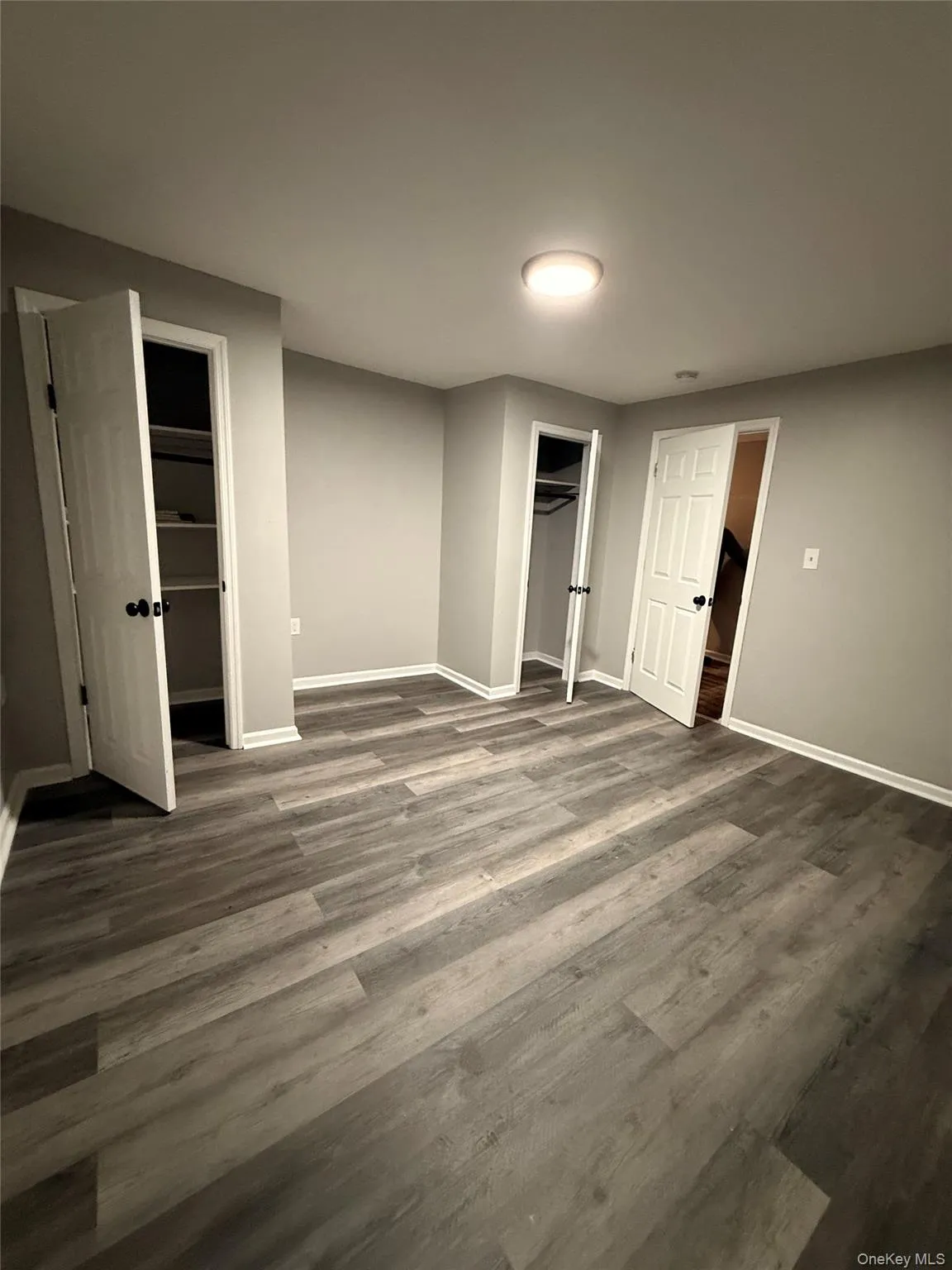 Unfurnished bedroom with dark wood-style floors and baseboards Unfurnished bedroom with dark wood-style floors and baseboards