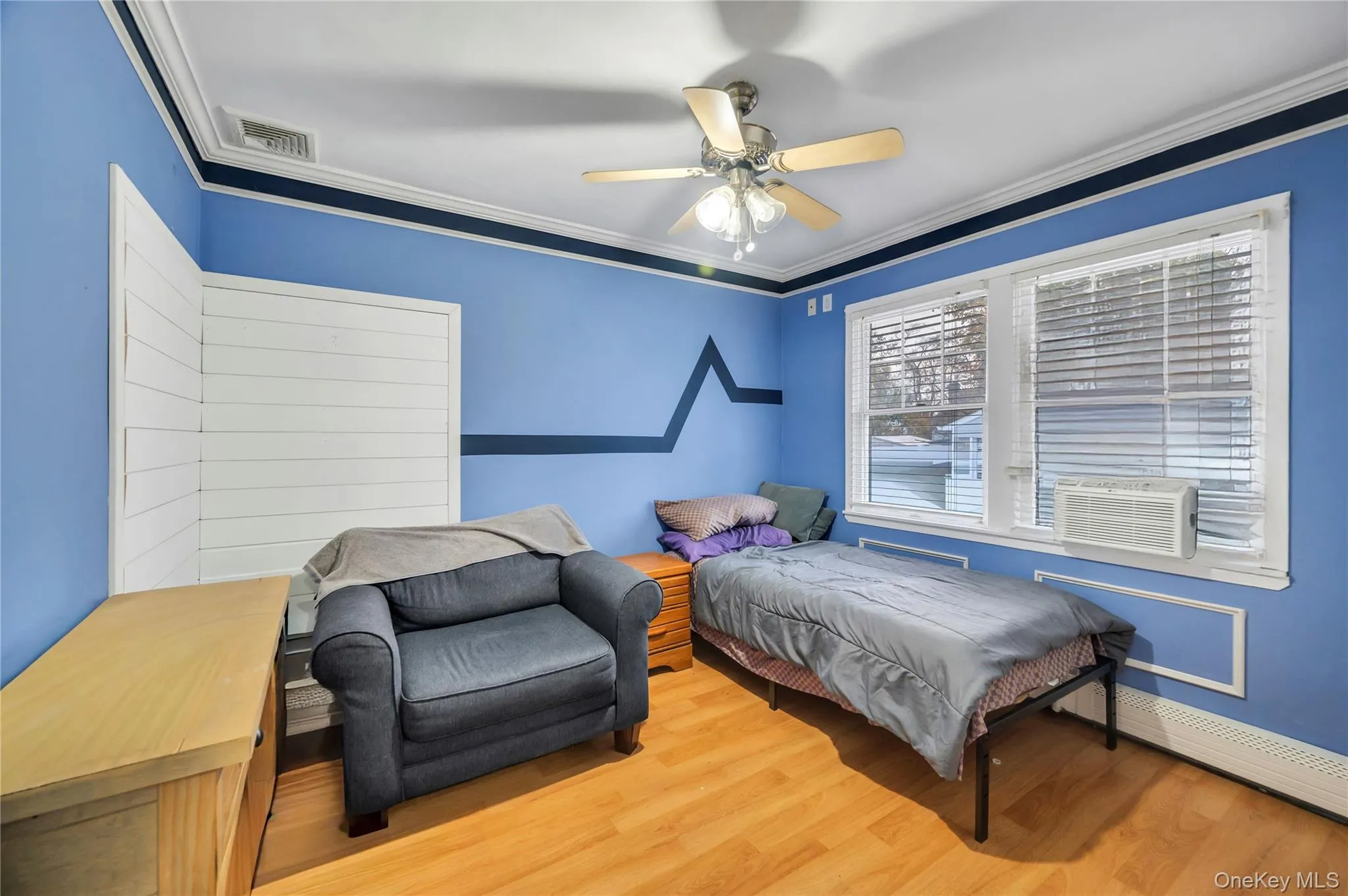 Bedroom with crown molding, wood finished floors, ceiling fan, a baseboard radiator, and cooling unit Bedroom with crown molding, wood finished floors, ceiling fan, a baseboard radiator, and cooling unit