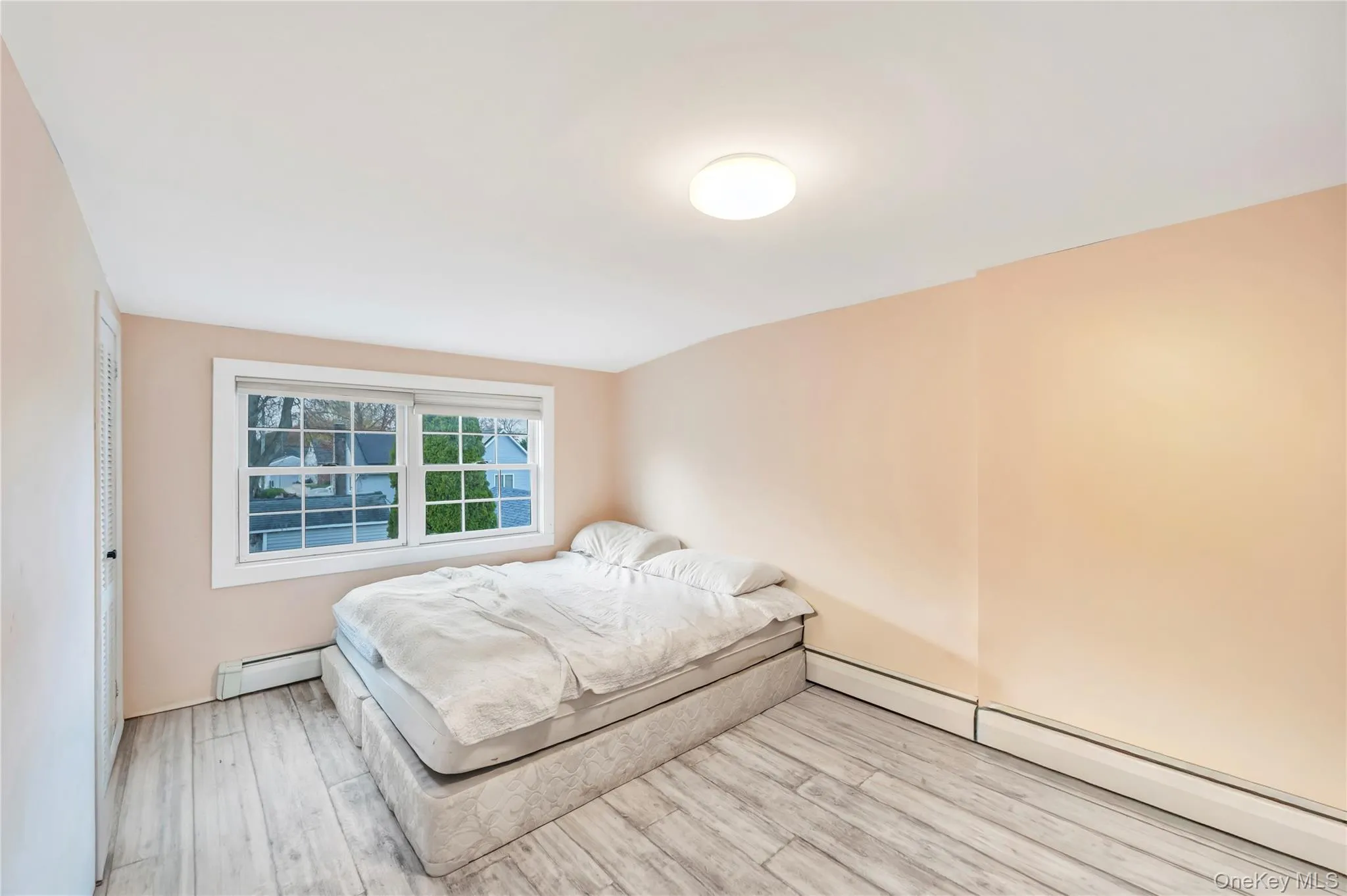 Bedroom with a baseboard heating unit and wood finished floors Bedroom with a baseboard heating unit and wood finished floors