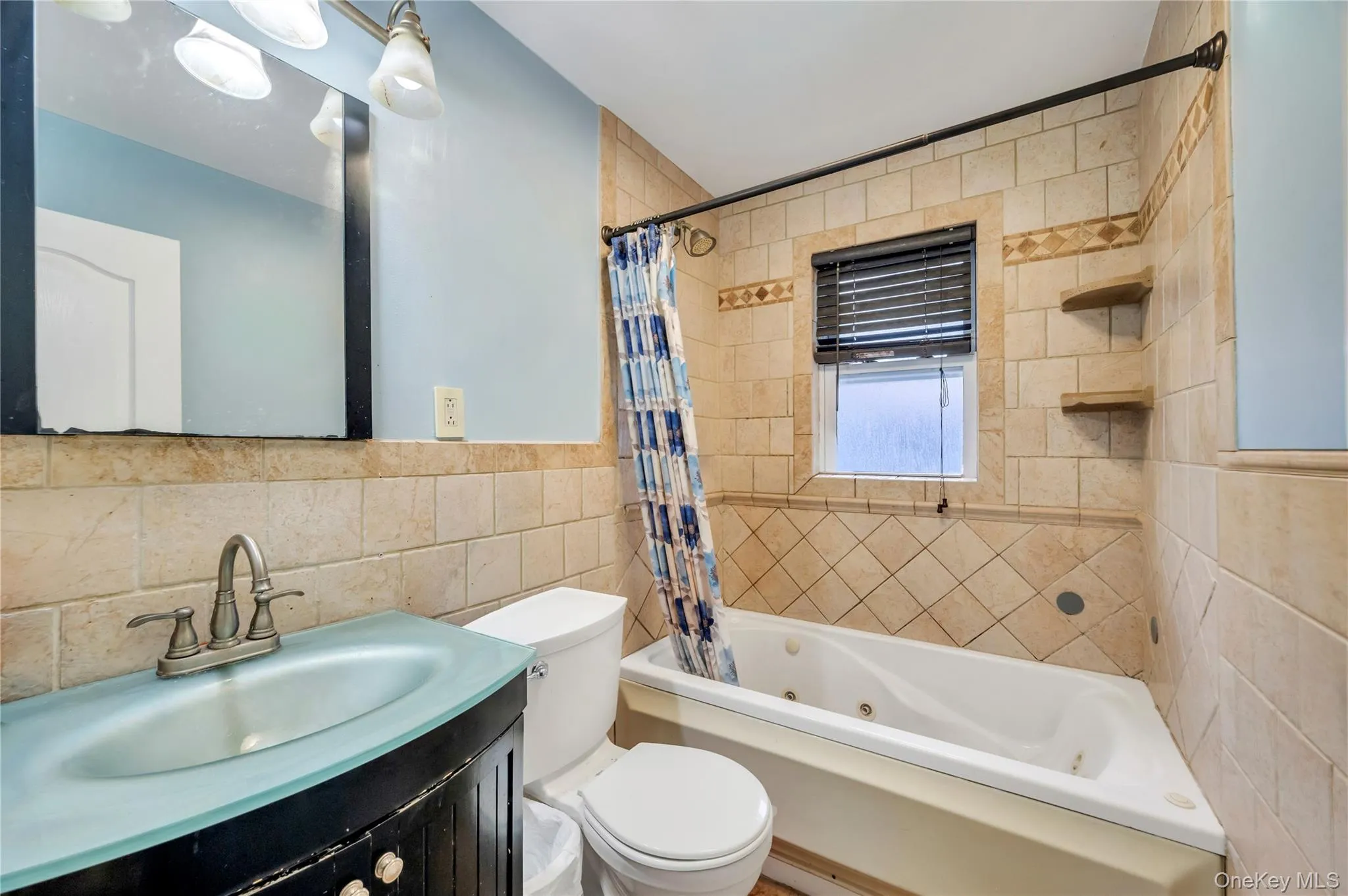 Full bath with tile walls, a combined bath / shower with jetted tub, and vanity Full bath with tile walls, a combined bath / shower with jetted tub, and vanity