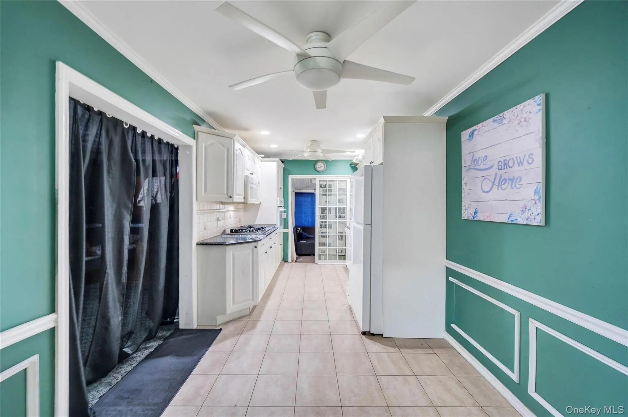 Kitchen with white cabinetry, light tile patterned floors, tasteful backsplash, ornamental molding, and freestanding refrigerator Kitchen with white cabinetry, light tile patterned floors, tasteful backsplash, ornamental molding, and freestanding refrigerator